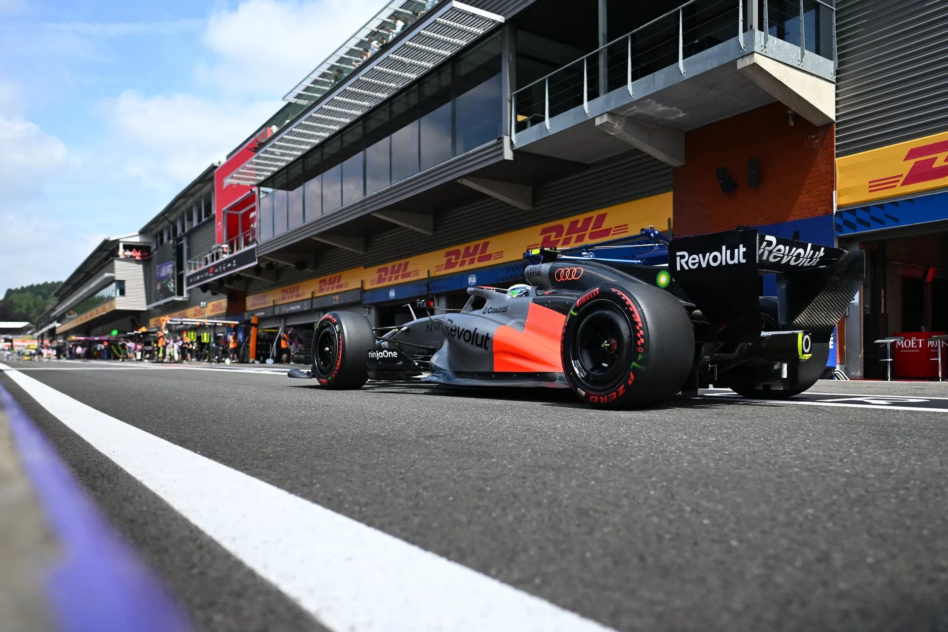 Audi R26 of Audi Revolut F1® Team in the pit lane with garages and team activity in the background