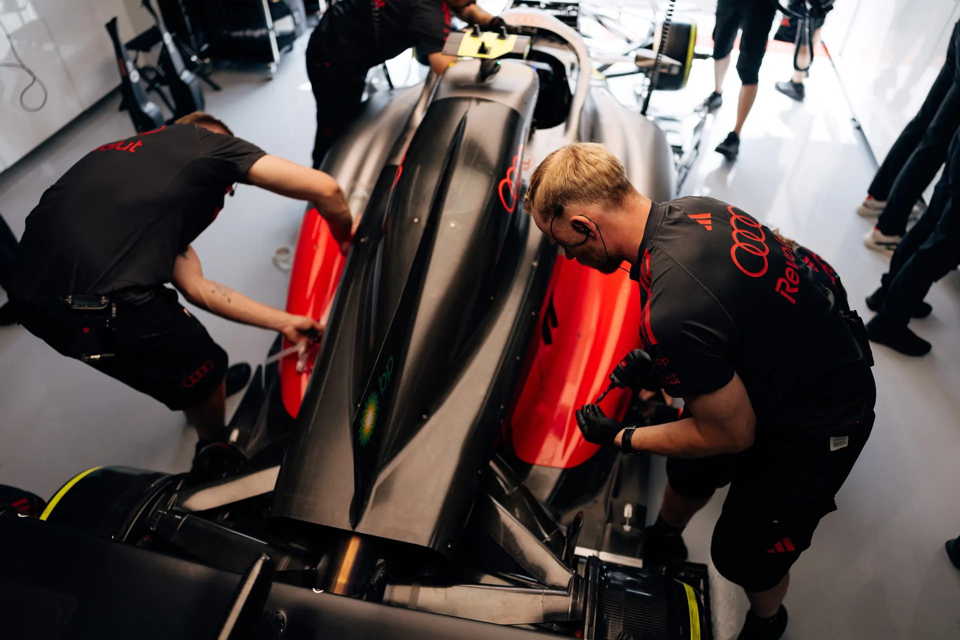 Audi Revolut F1® Team mechanics work on the Audi R26 inside the garage, adjusting bodywork on both sides of the car during qualifying preparation