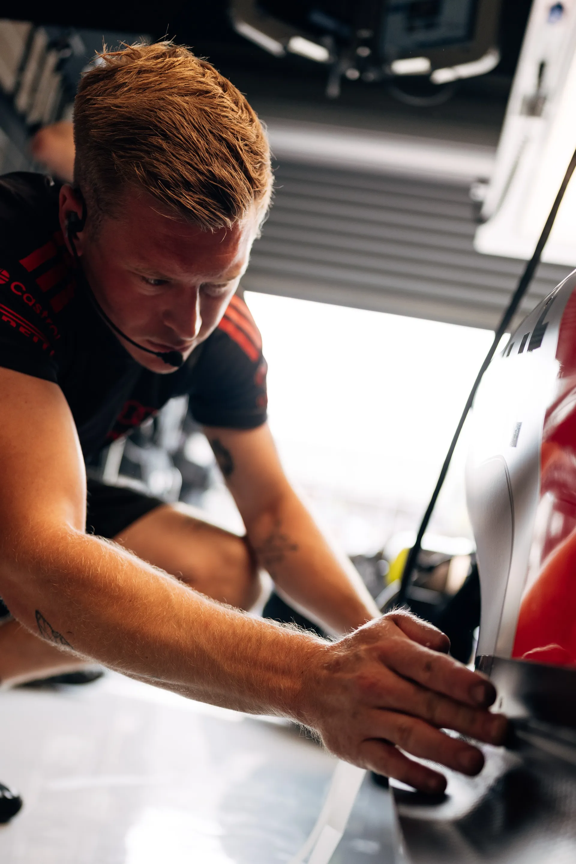 Audi Revolut F1® Team mechanic closely inspects and adjusts a front bodywork component of the Audi R26 inside the garage