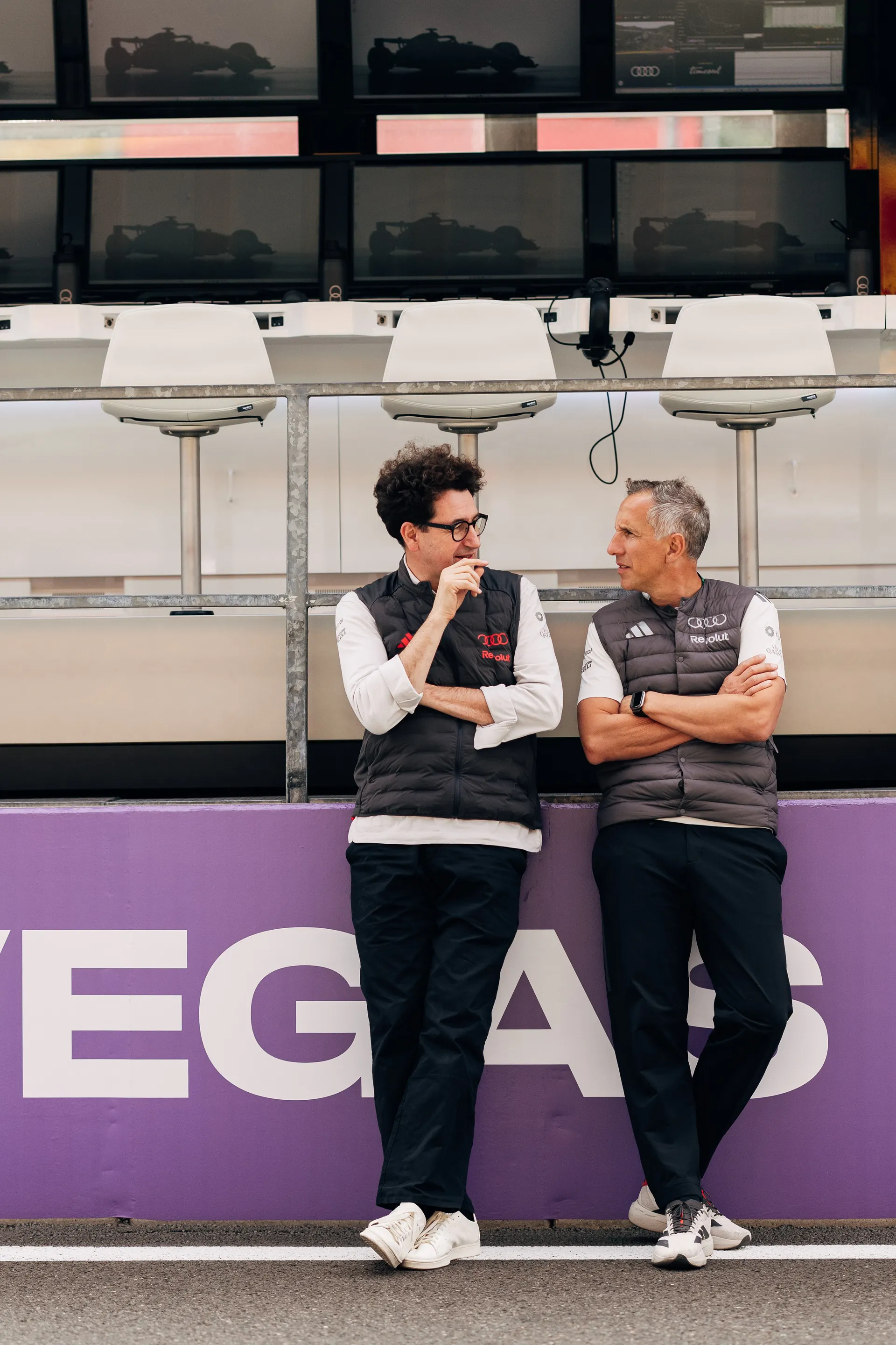 Mattia Binotto Audi Revolut F1® Team stand trackside in front of pit wall screens, discussing data and observing the session during qualifying