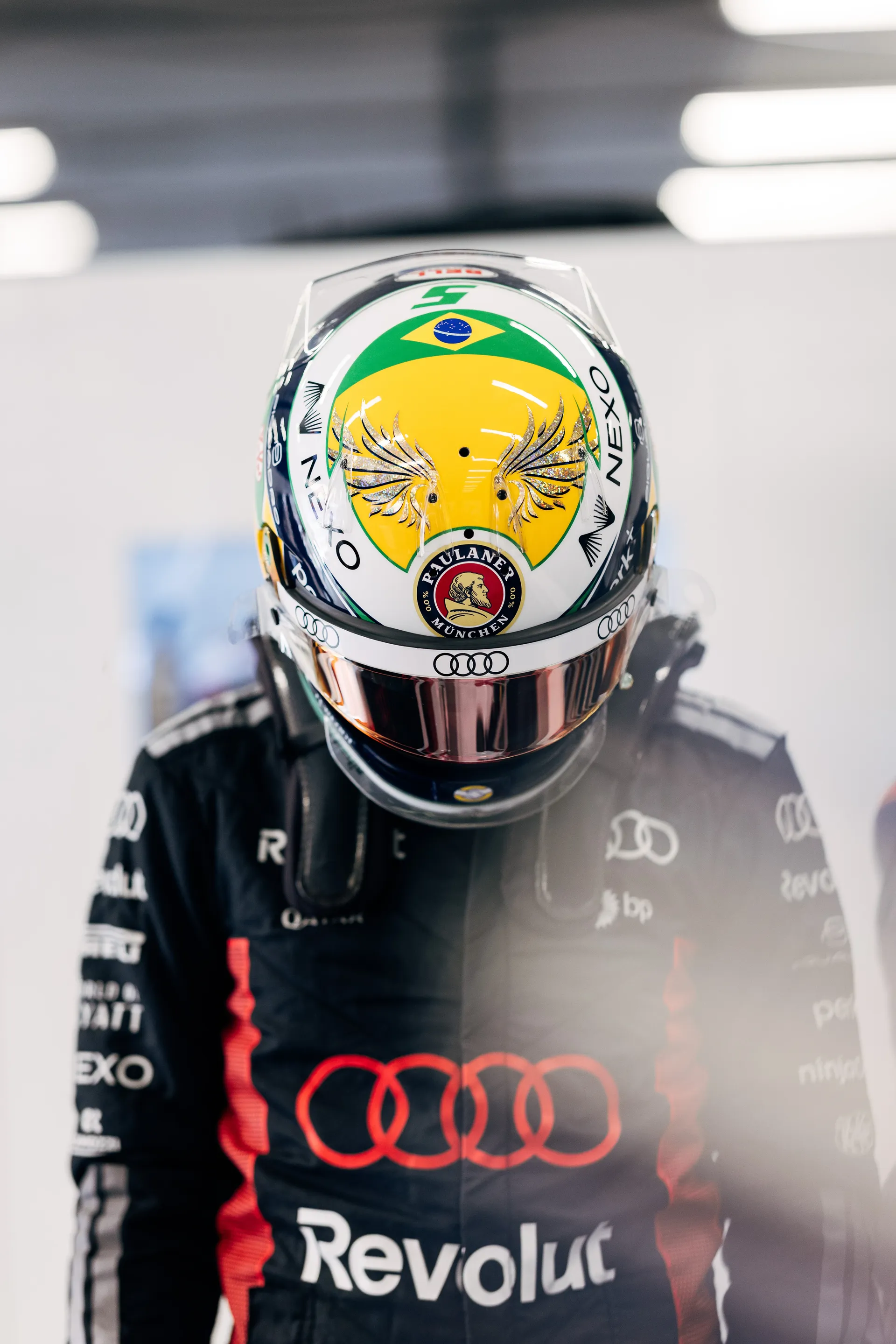 Gabriel Bortoleto wearing his helmet stands inside the Audi Revolut F1® Team garage, preparing for qualifying in race suit