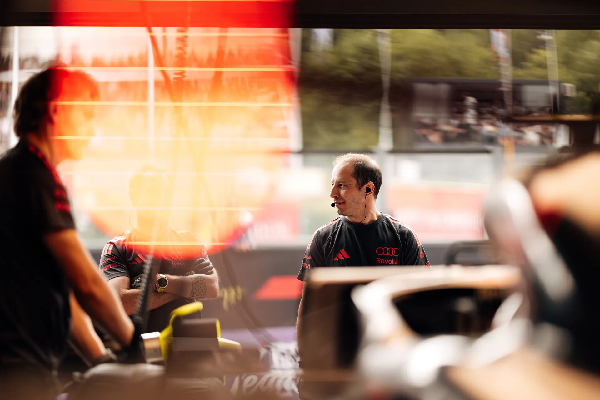 Audi Revolut F1® Team engineer stands in the garage with headset, monitoring the session while looking towards the pit lane