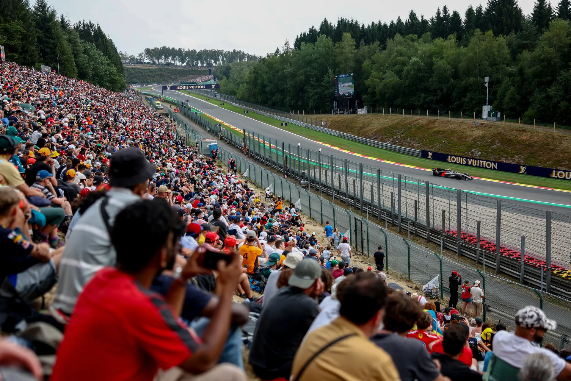 Crowded grandstands overlooking the circuit at Spa Francorchamps as a Formula 1 car passes during qualifying