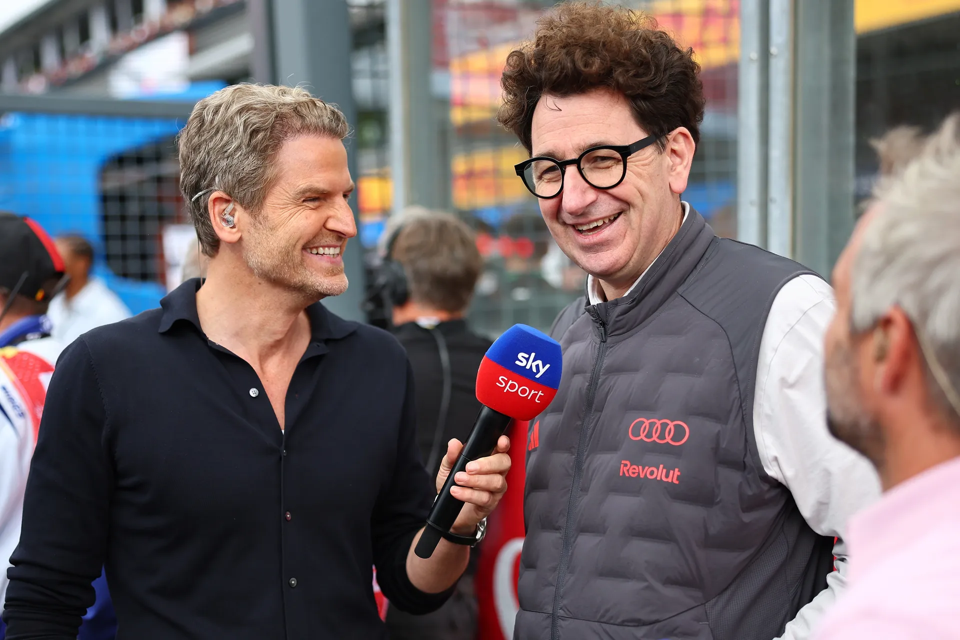 Mattia Binotto is interviewed in the paddock, holding a Sky Sport microphone alongside a presenter.