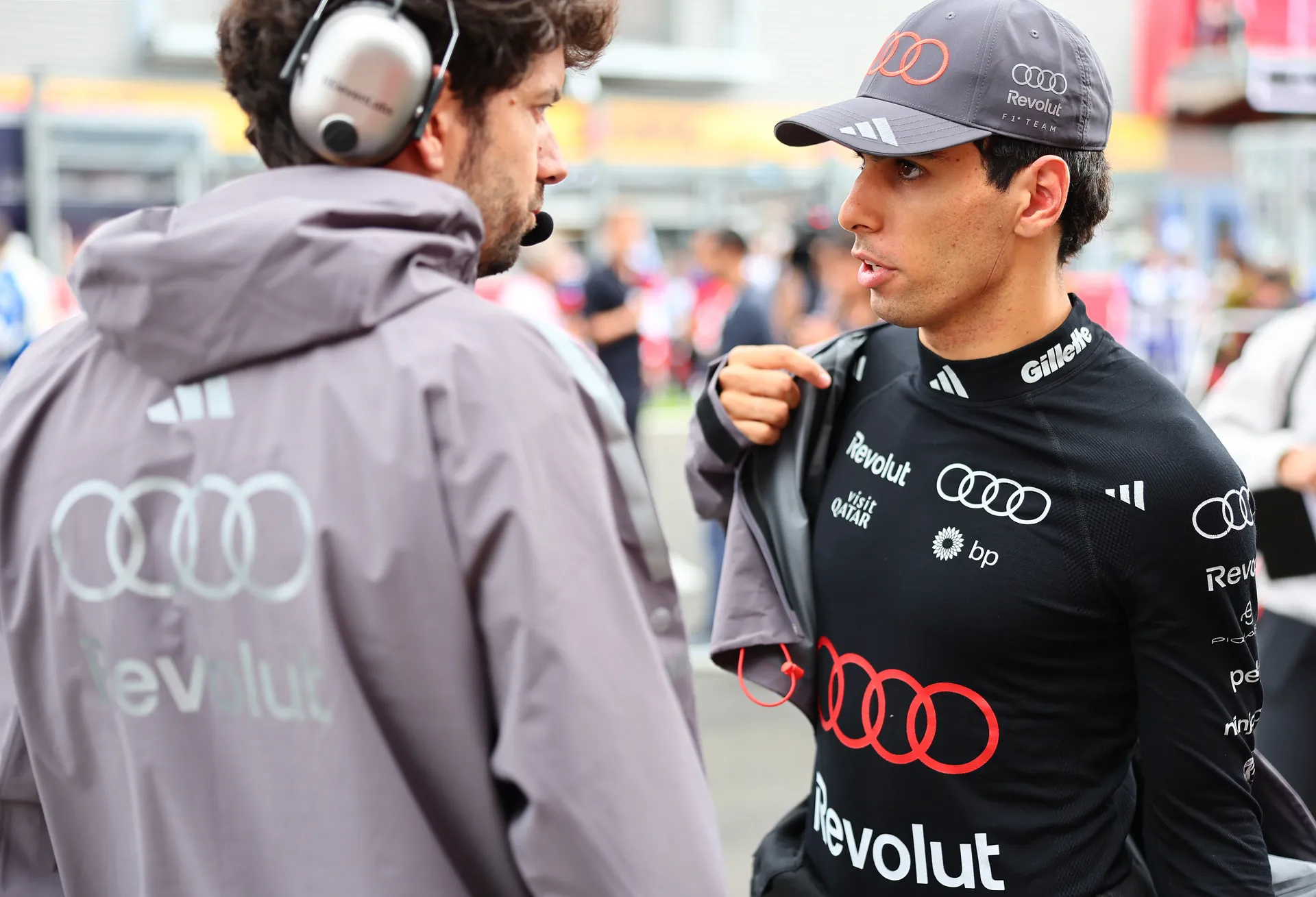 Gabriel Bortoleto talks to an Audi Revolut F1® Team engineer while preparing in his race base layer and team cap.