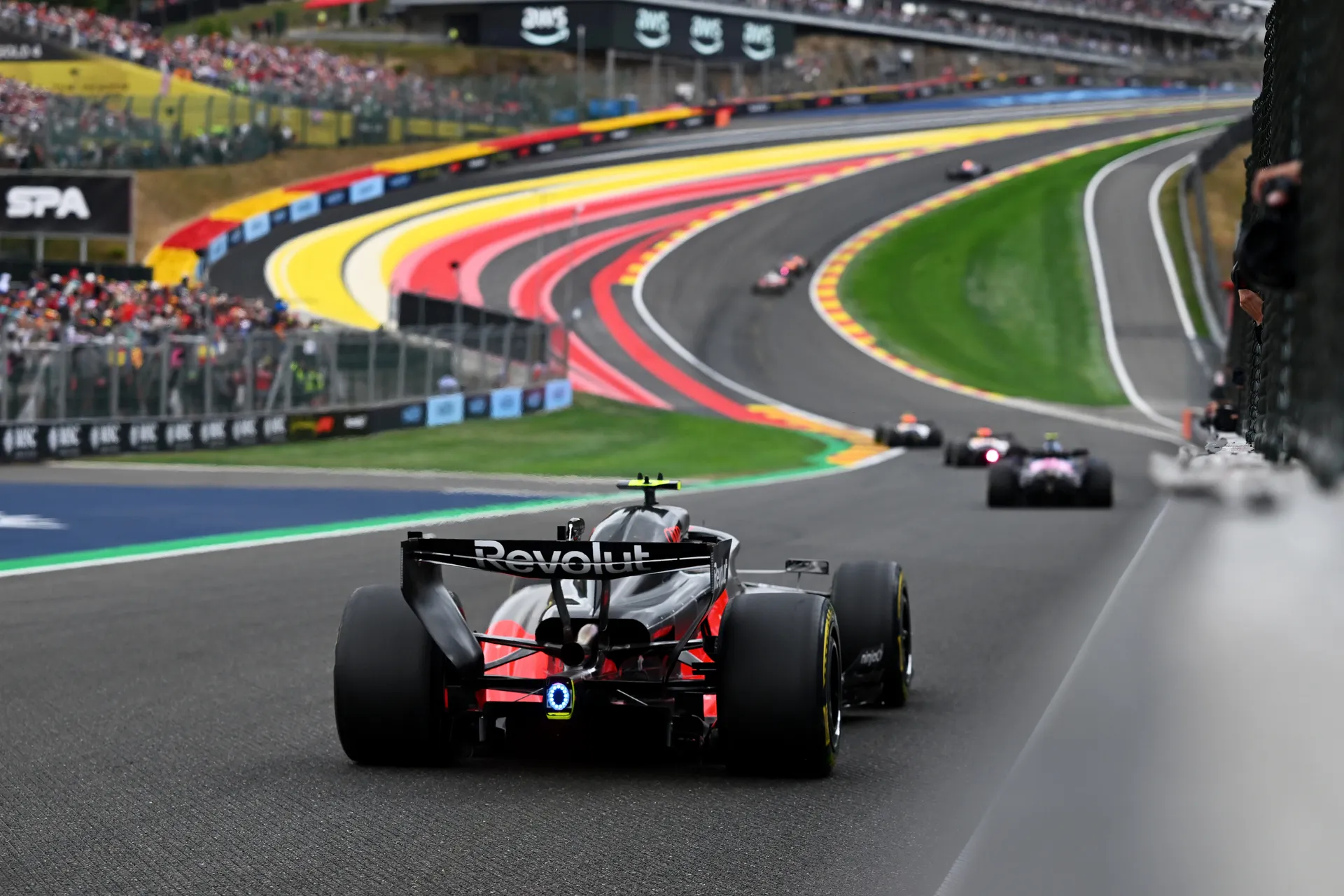 Rear view of the Audi R26 driving uphill through Spa-Francorchamps, with multiple cars ahead on the racing line.