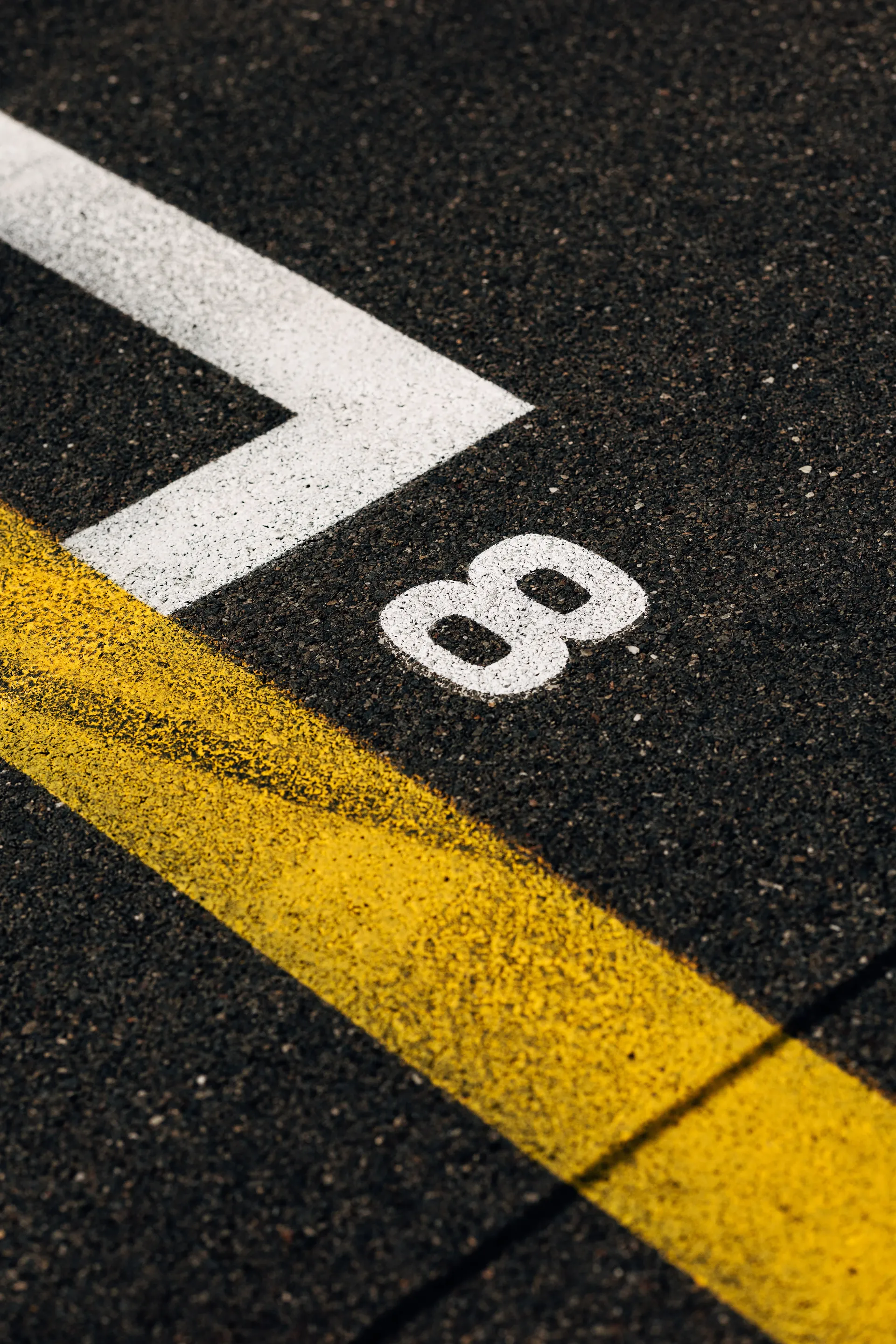 Close-up of Spa-Francorchamps track surface with painted grid marking “88” and yellow line on asphalt during a Formula One weekend.