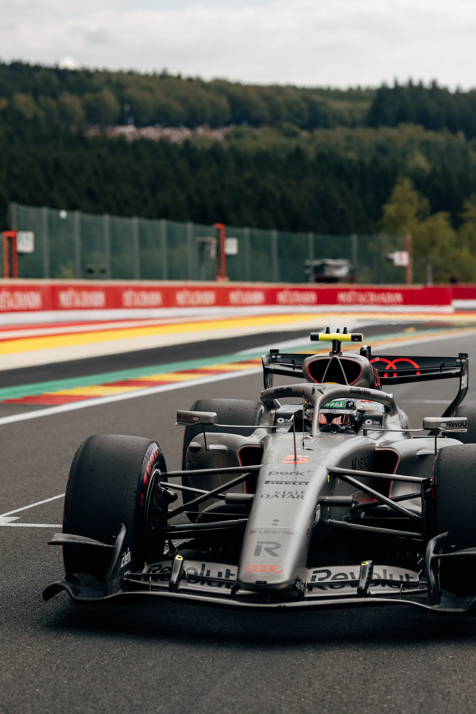 Audi Revolut F1® Team Formula One car drives along the track at Spa-Francorchamps, captured head-on with the circuit and forest in the background.