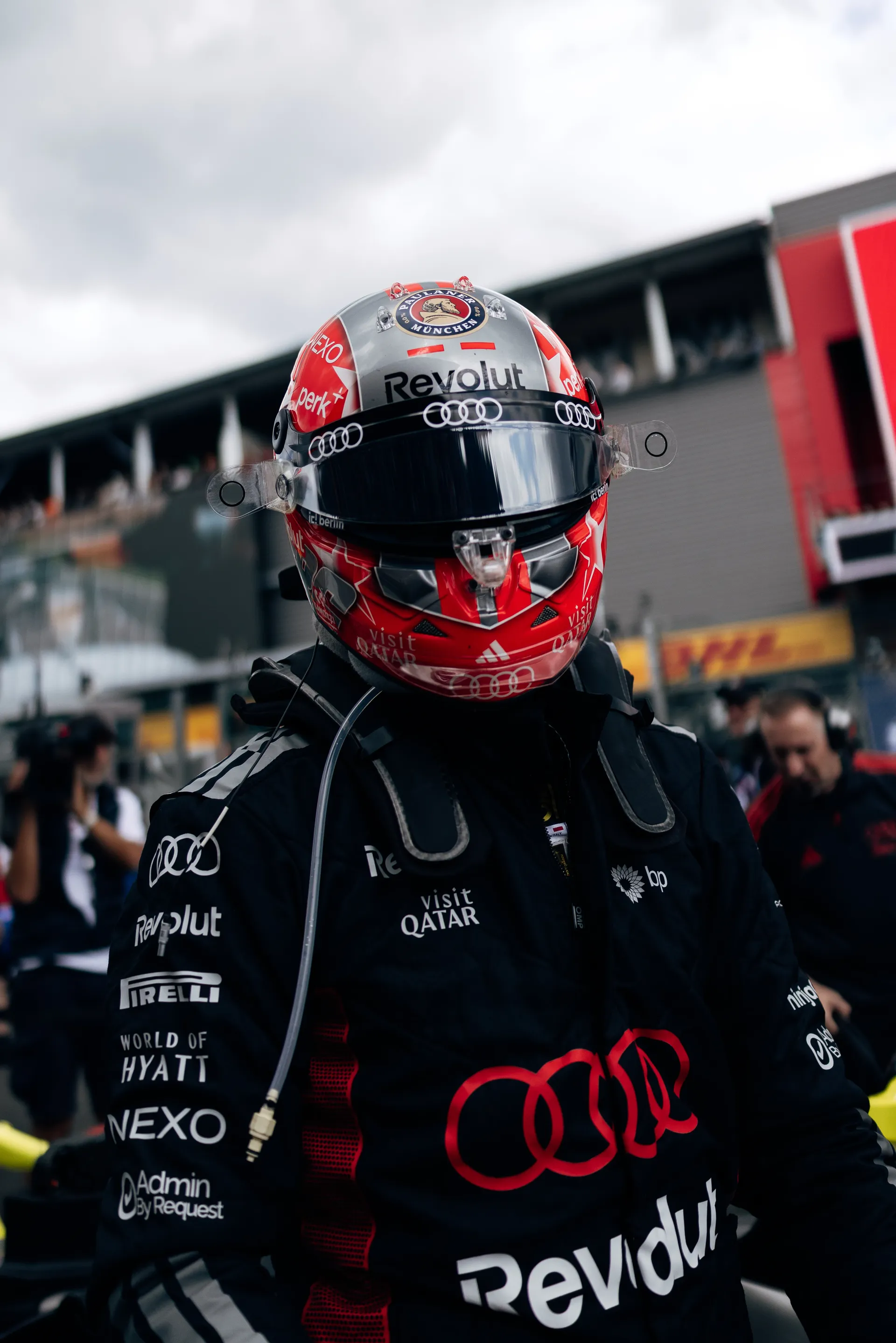 Nico Hulkenberg stands on the grid in Audi Revolut F1® Team race suit wearing a helmet, moments before the session at Spa-Francorchamps.