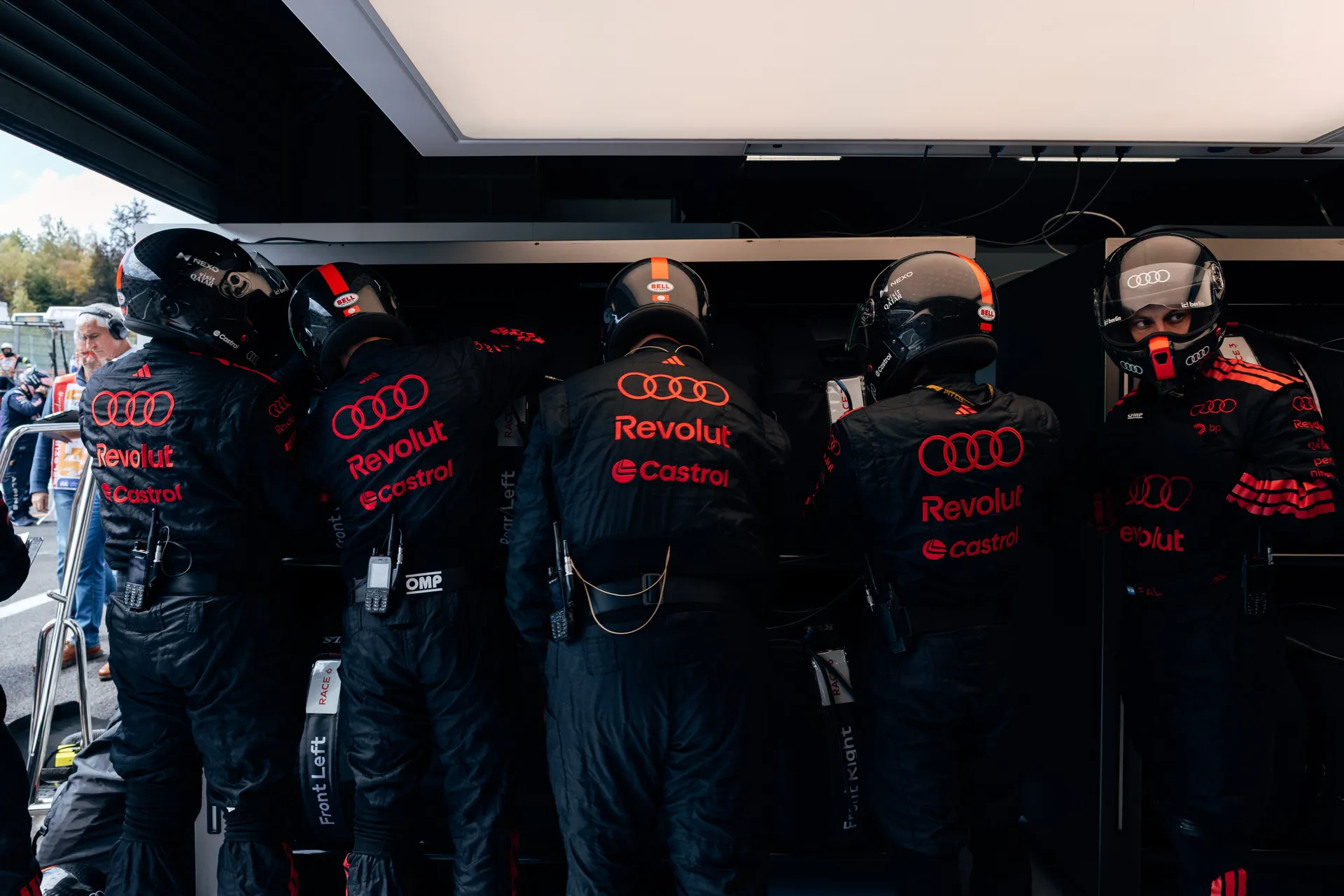 Audi Revolut F1® Team mechanics working together inside the garage on an Audi Revolut F1® Team R26 during race preparation