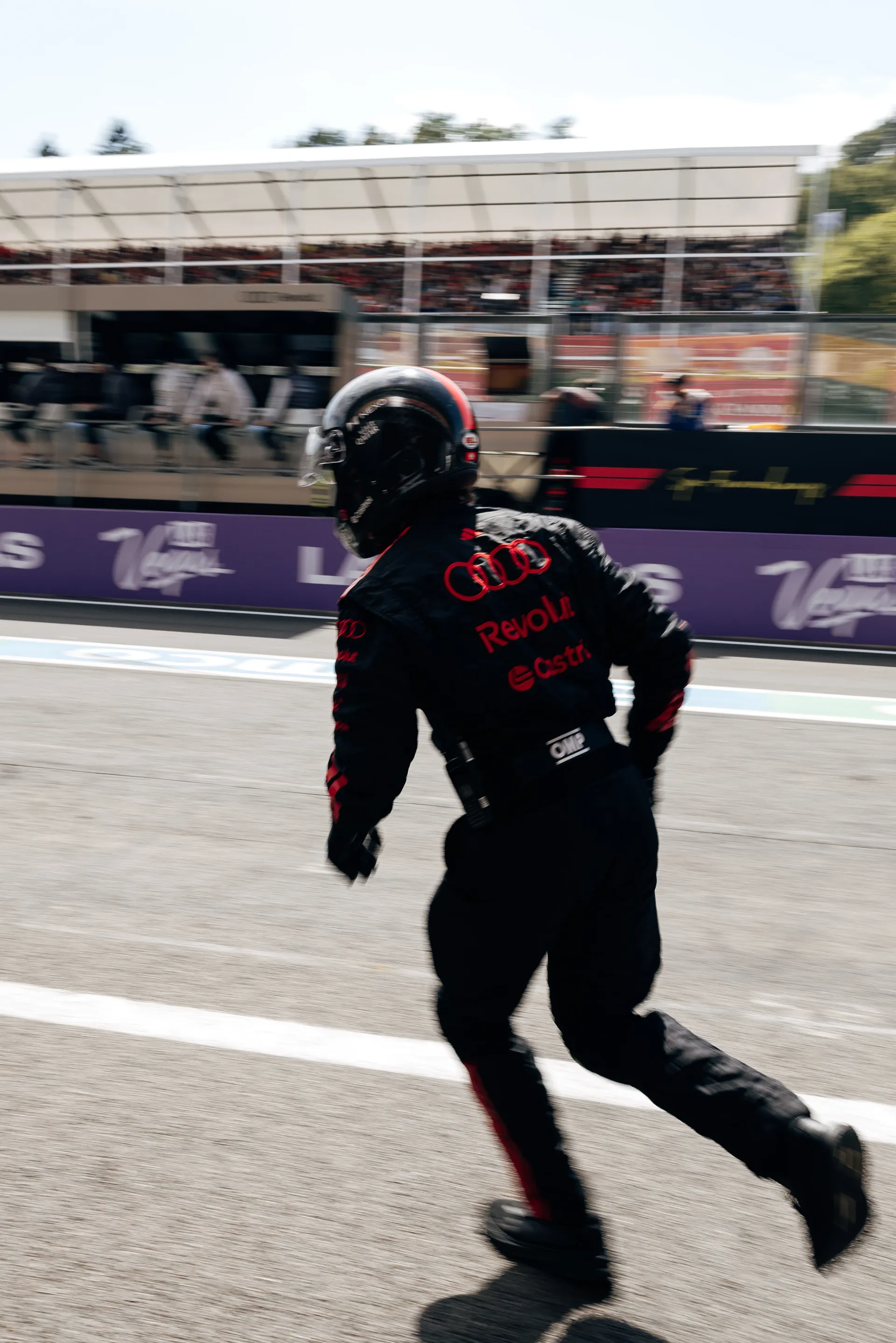 Audi Revolut F1® Team pit crew member sprinting along the pit lane in full gear during an active race moment