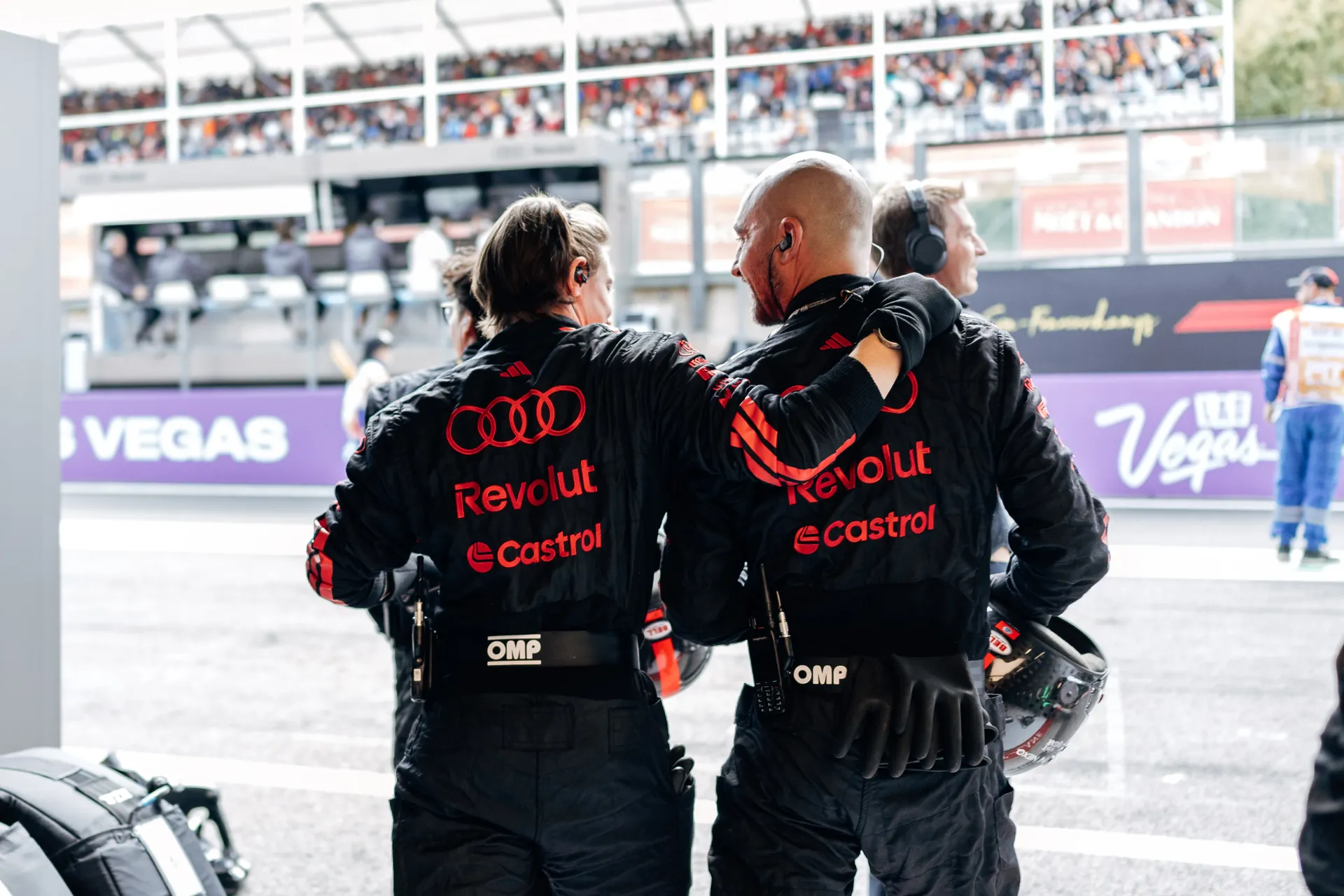 Audi Revolut F1® Team crew member guiding an Audi Revolut F1® Team R26 into position on the grid, pointing towards the front wheel
