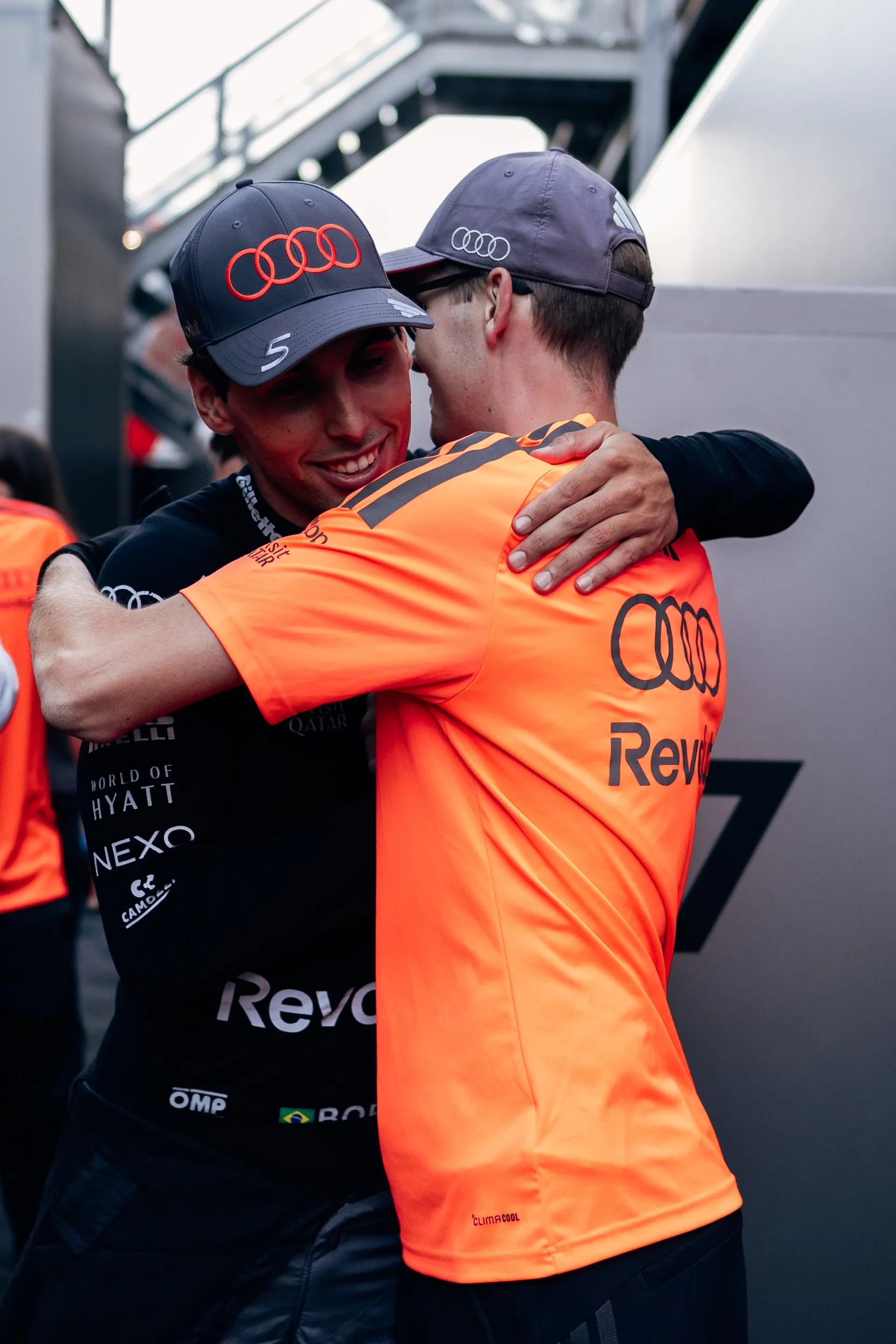 Audi Revolut F1® Team member smiling while hugging Gabriel Bortoleto in front of the team hospitality unit at the circuit