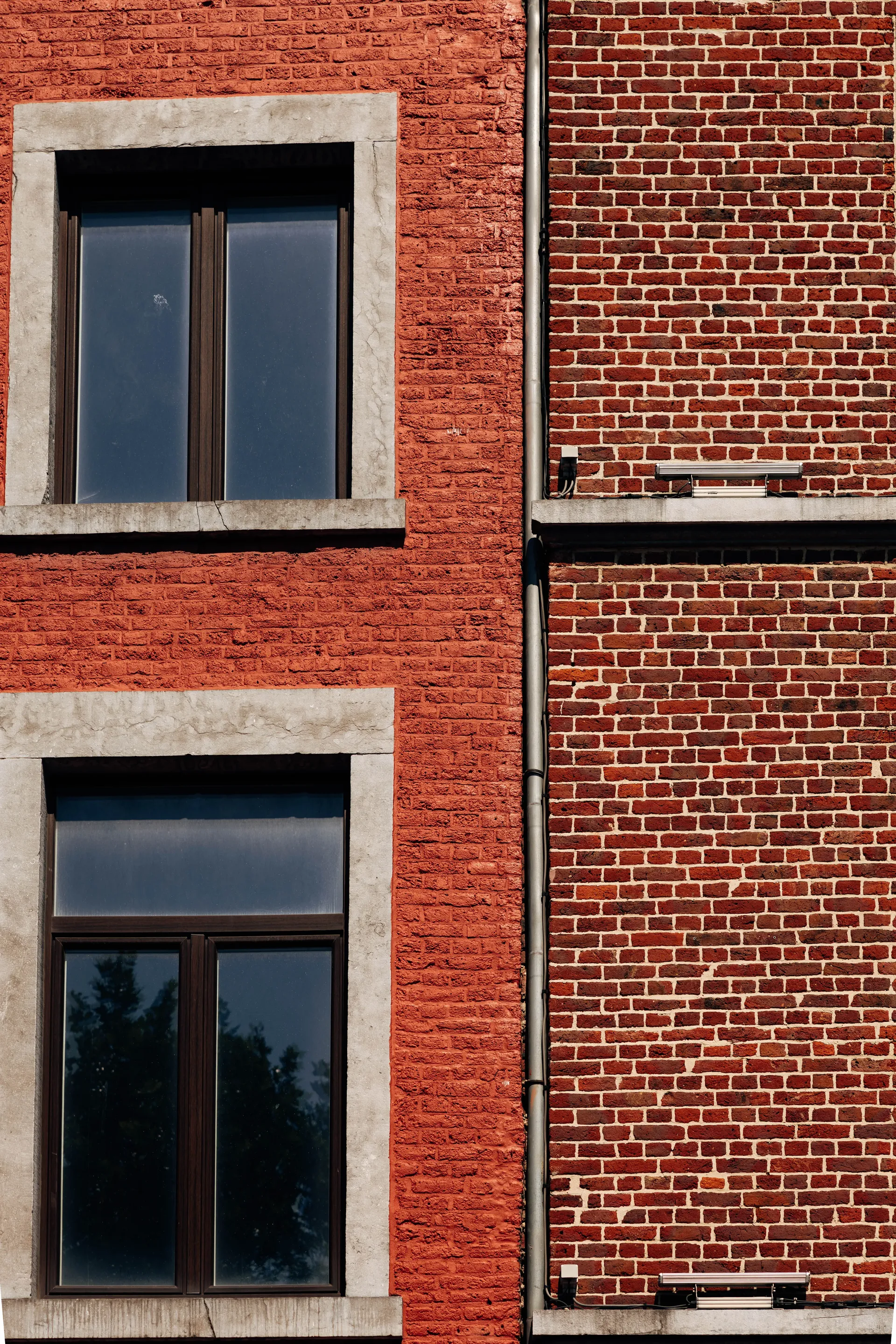 Close-up of a traditional Belgian brick façade with stone-framed windows.