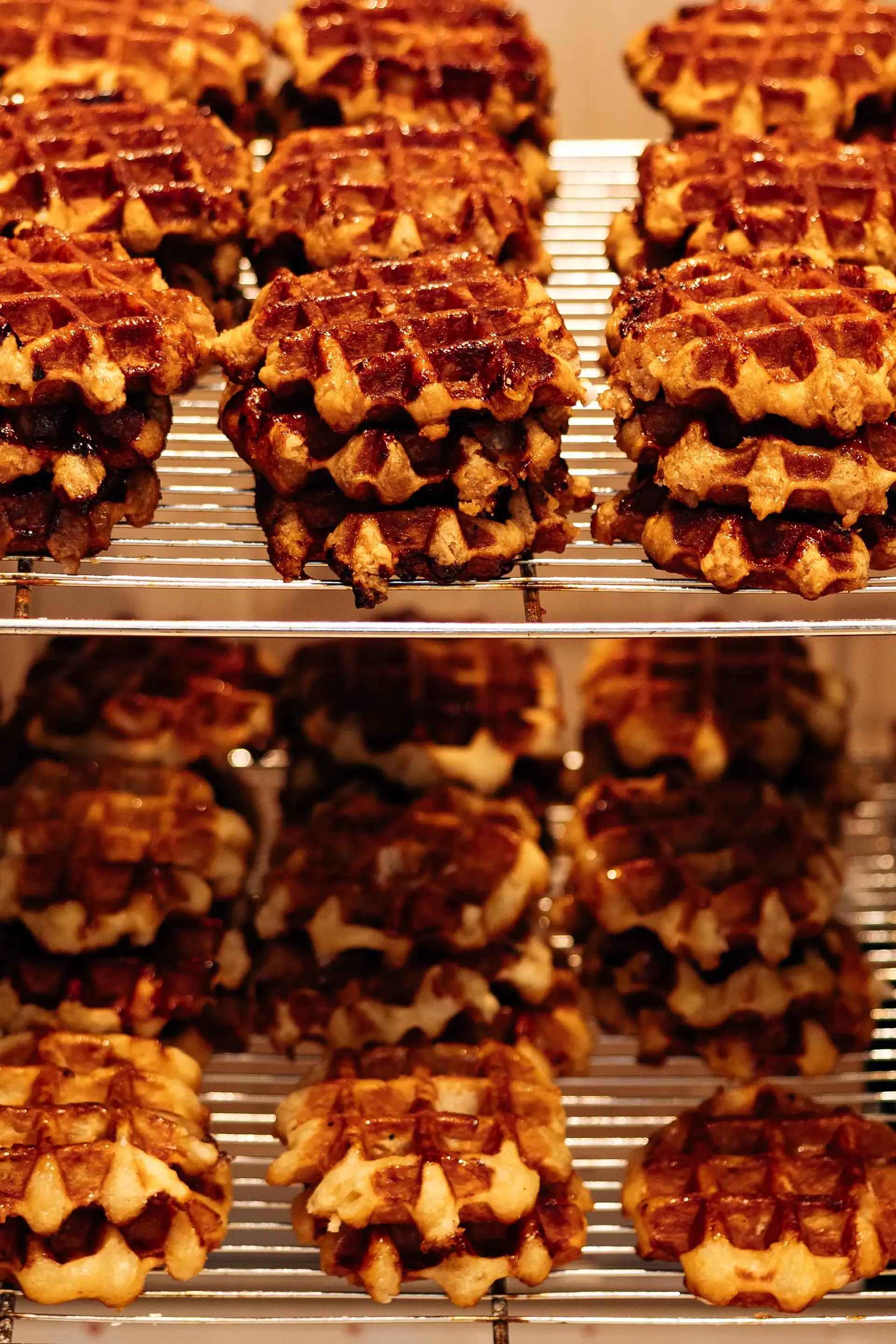 Fresh Belgian waffles cooling on racks with crisp, caramelised edges.
