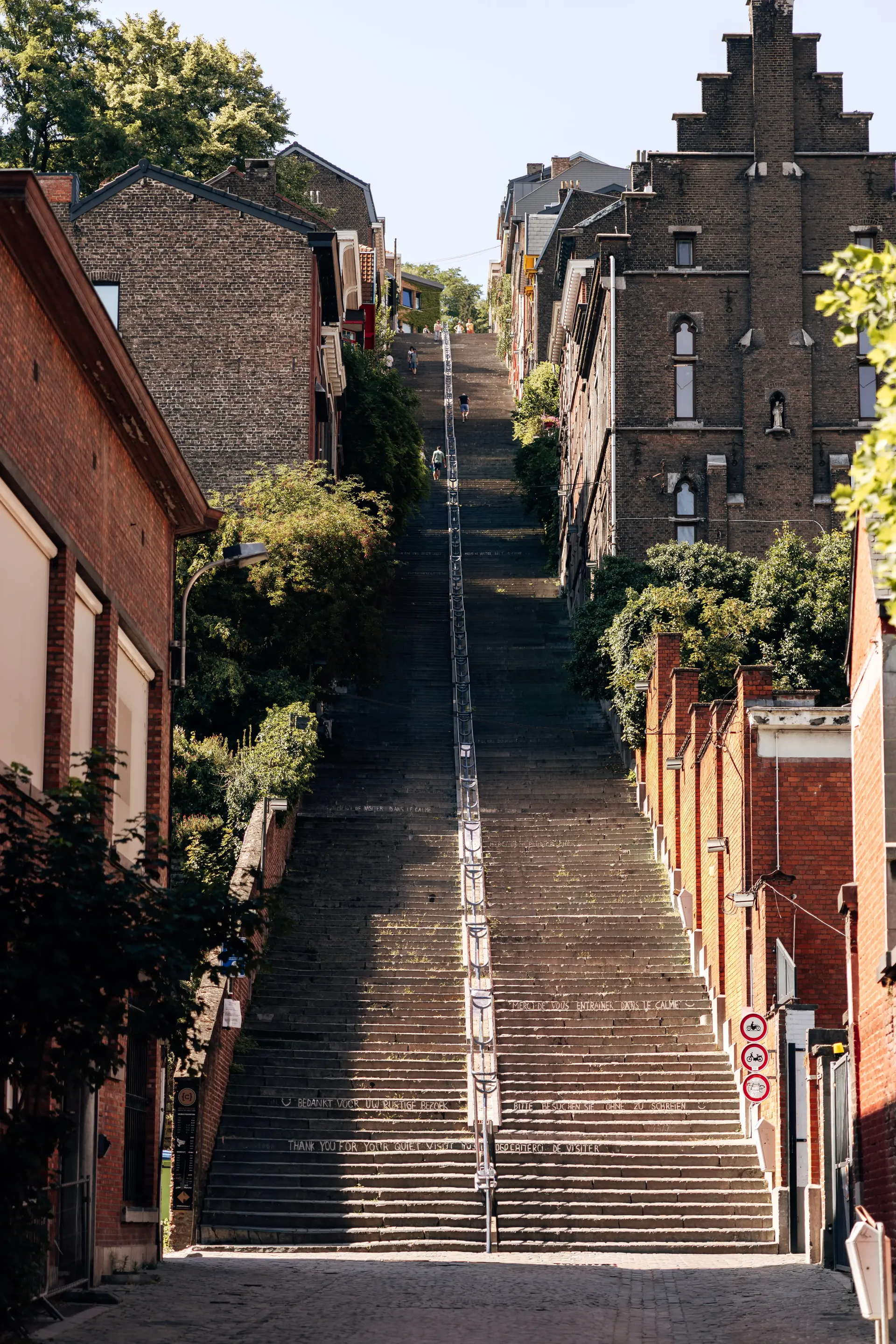 Steep stone staircase between historic buildings leading uphill in a Belgian town.
