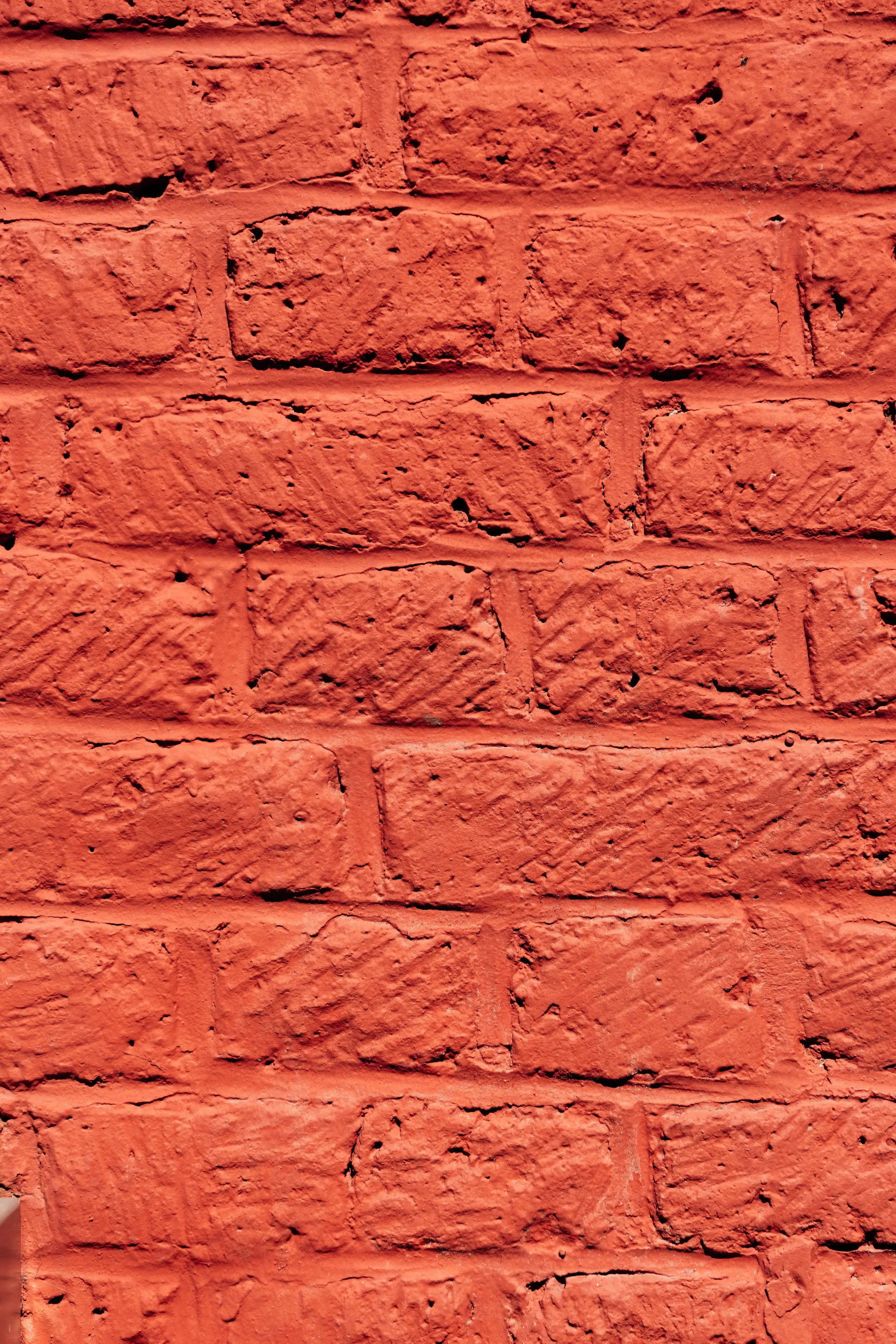 Close-up of a textured red-painted brick wall.