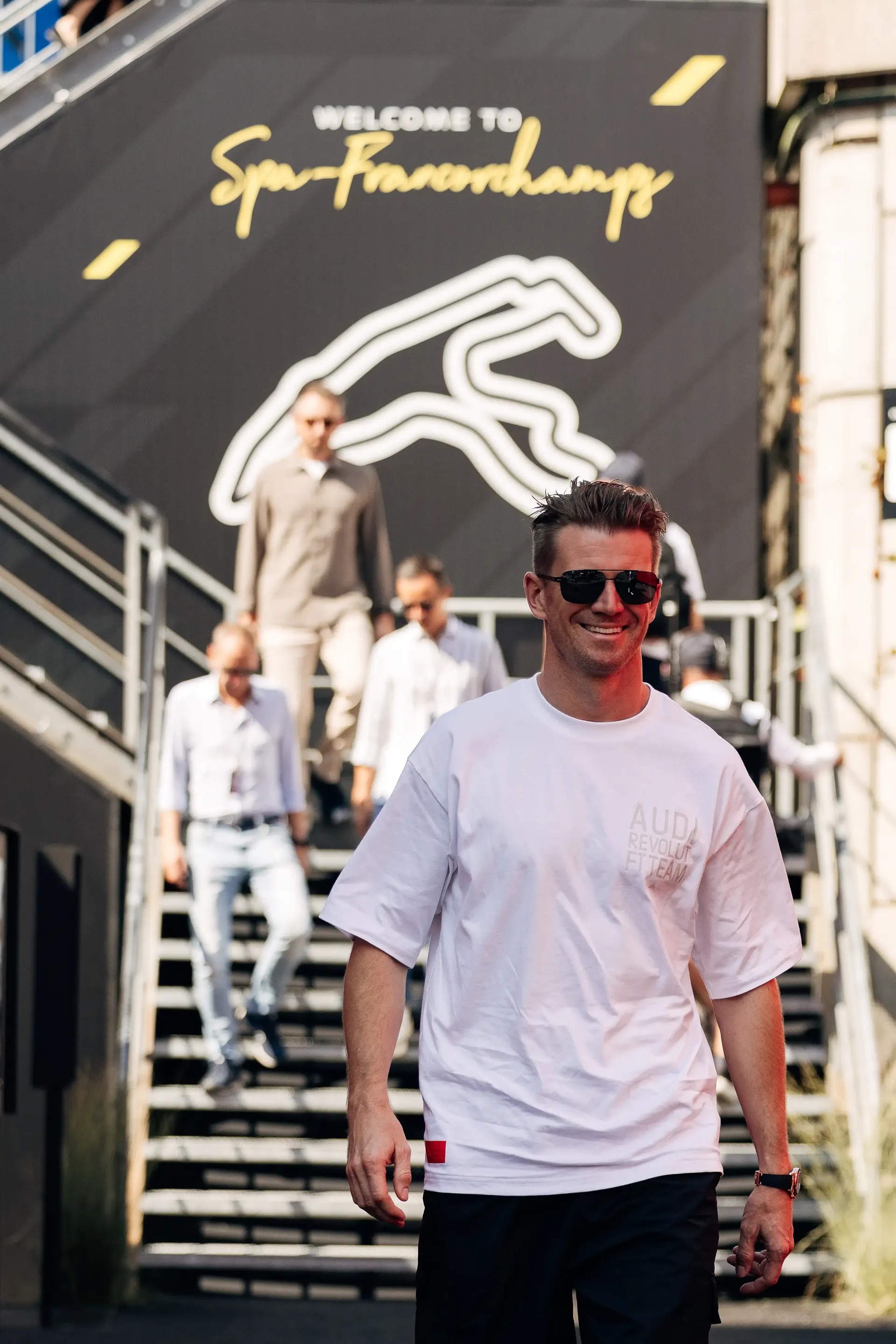 Nico Hulkenberg, Audi Revolut F1® Team driver, arrives at the Spa-Francorchamps paddock in elevated fanwear, wearing sunglasses and smiling