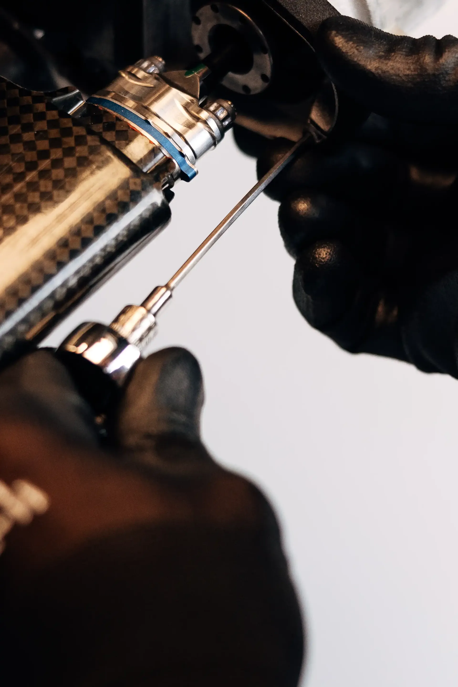 Close-up of an Audi Revolut F1® Team mechanic using a precision tool while assembling a Formula 1® car component inside the Audi Revolut F1® Team garage.