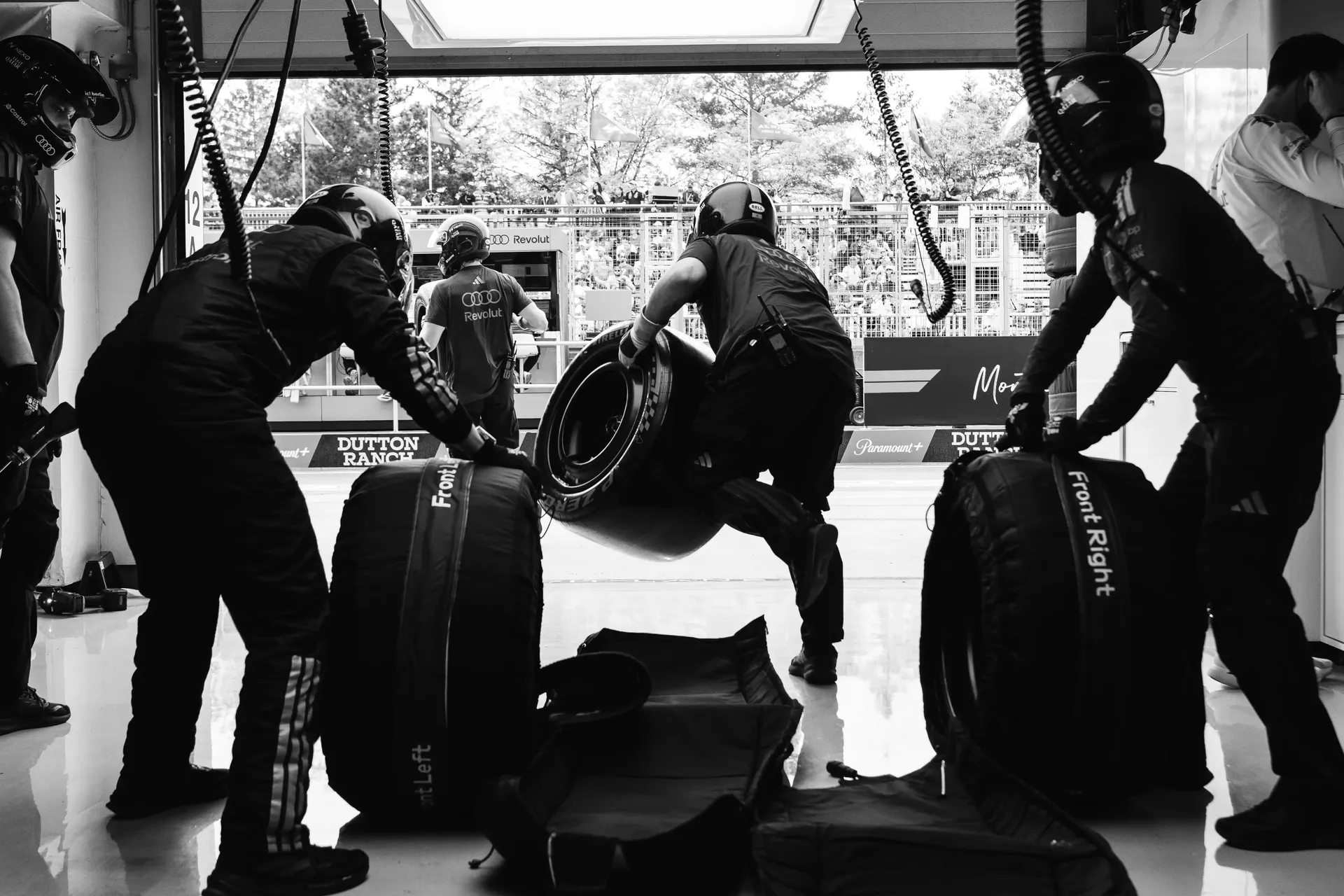 Black and white shot of crew mechanics of the the Audi Revolut F1® Team changing tires inside the garage at the Canada Grand Prix 2026