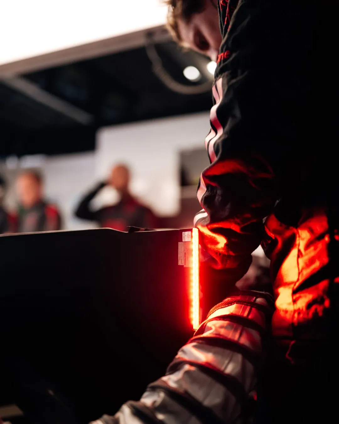 Close-up of Audi Revolut F1® Team mechanic handling equipment under red lighting in the garage.