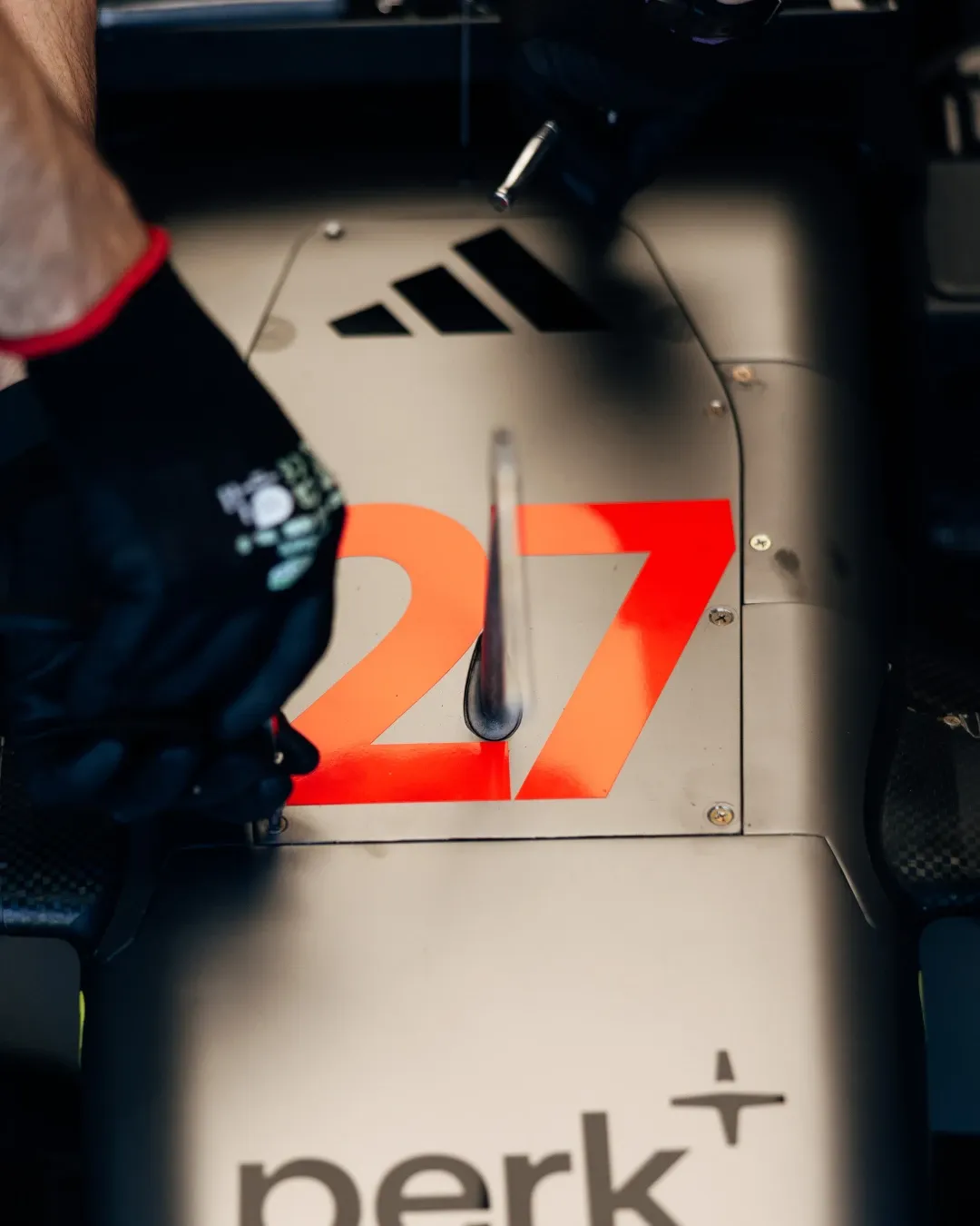 Detail shot of Formula 1 car body with number 27, Nico Hulkenberg’s car, during garage preparation.