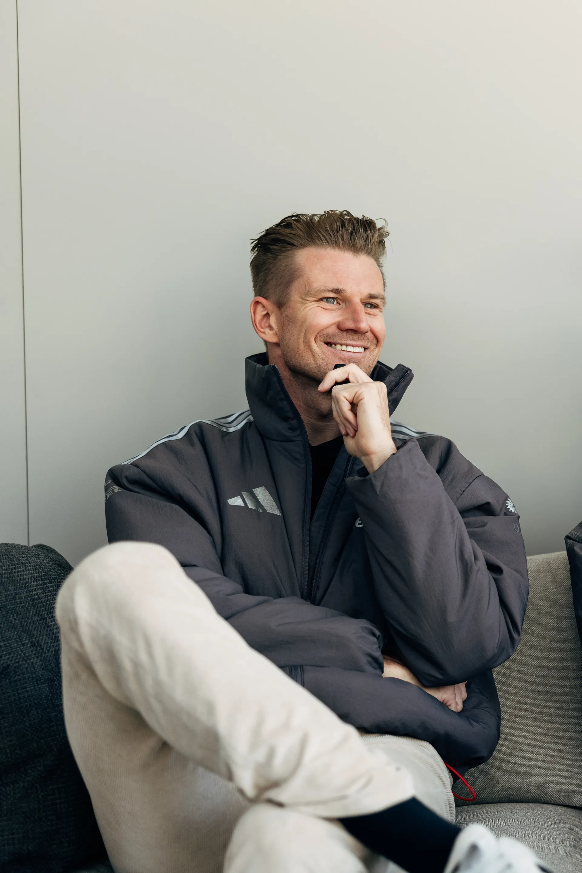 Nico Hulkenberg seated casually, smiling in Audi Revolut F1® Team jacket.