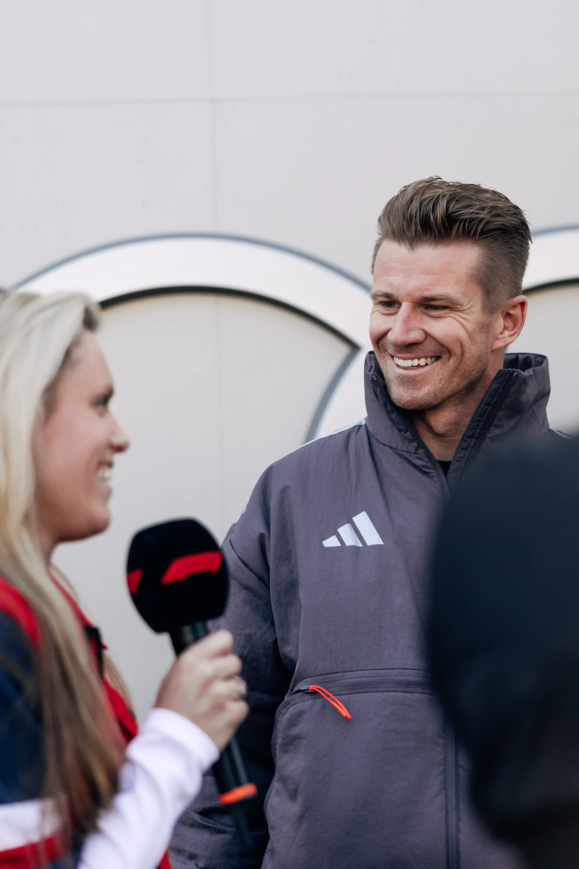 Nico Hulkenberg being interviewed trackside, smiling during conversation.
