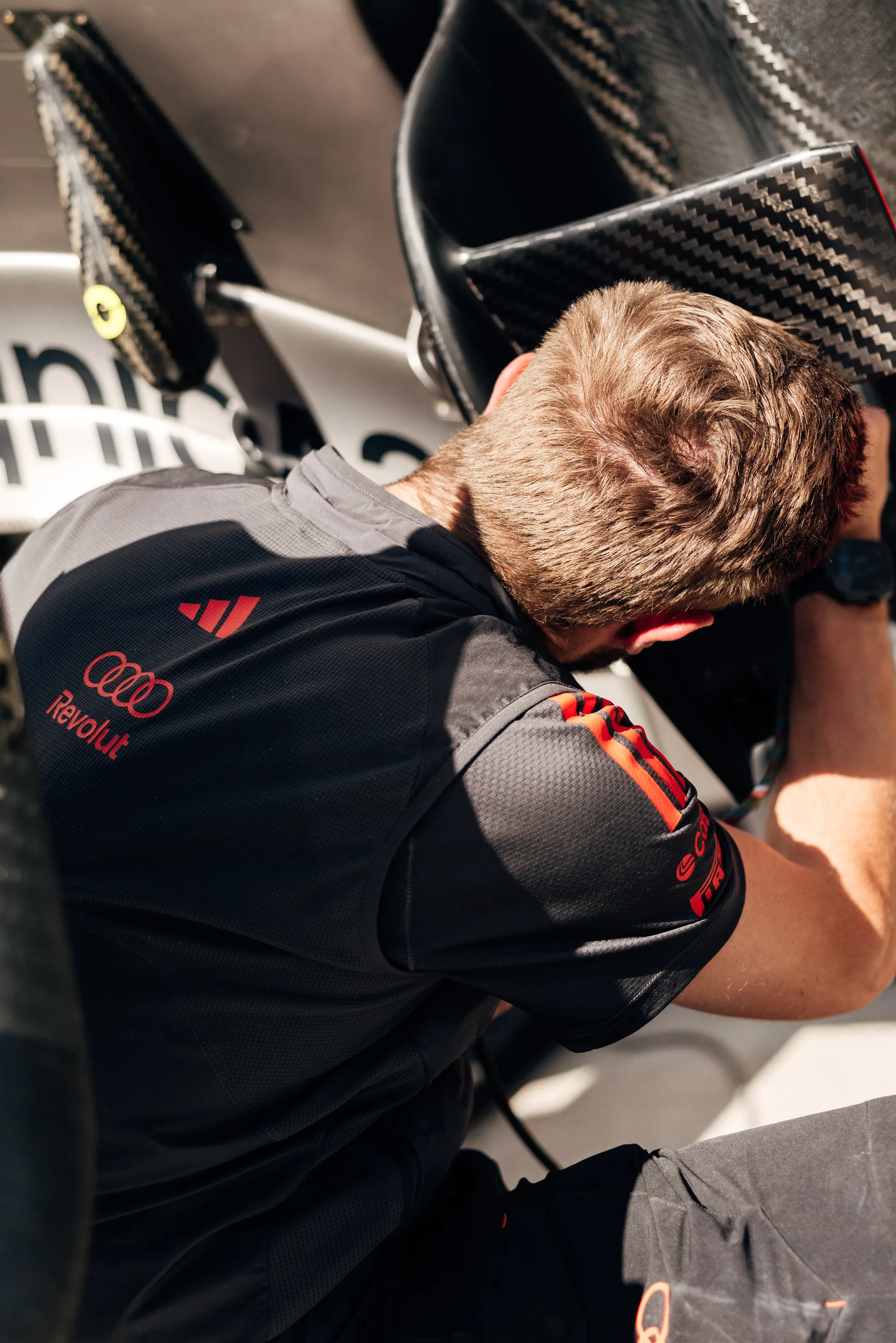 Close-up of mechanic working on car components, showing Audi Revolut F1® Team branding on uniform.