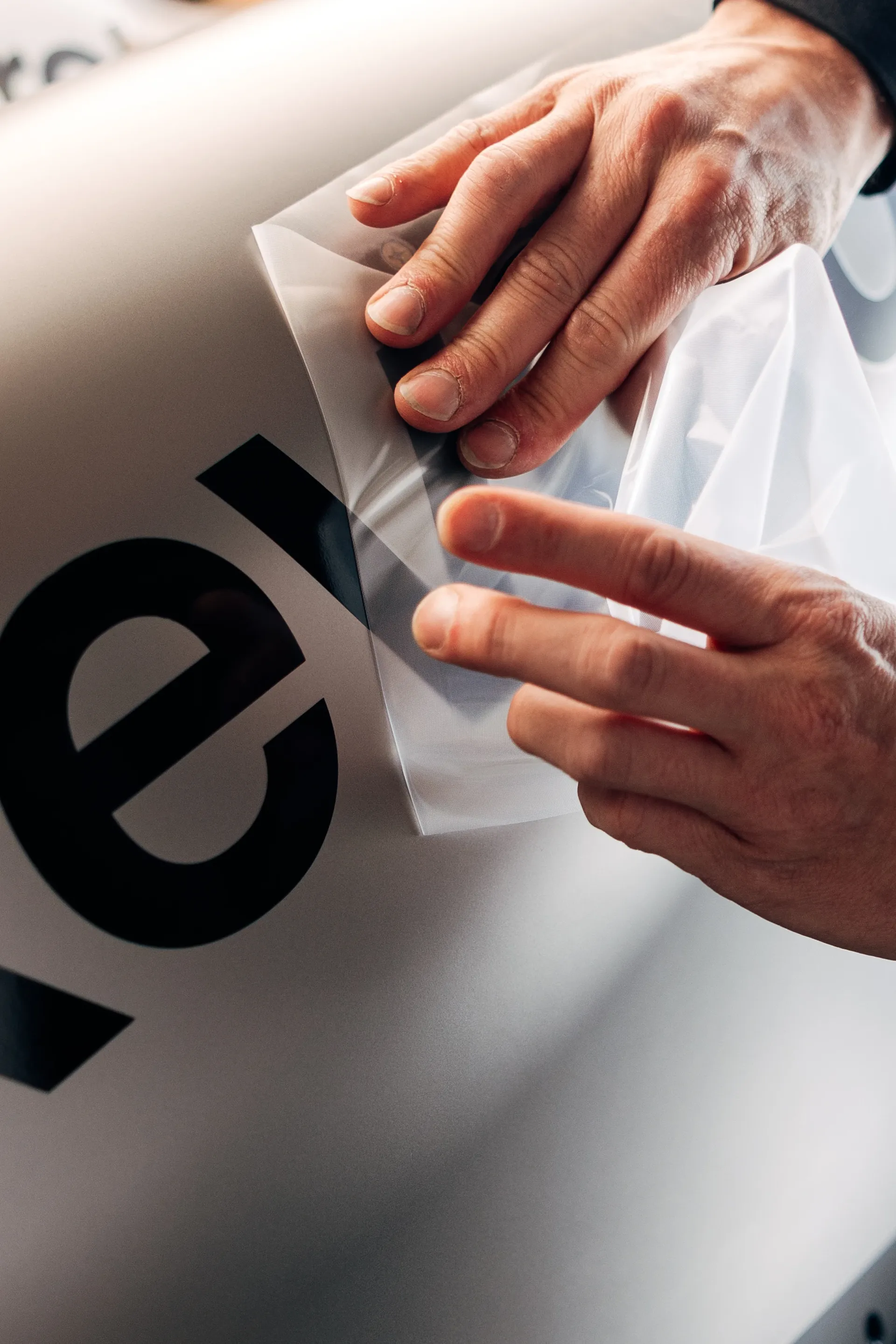 Close-up of hands applying protective film or decal on the Formula 1 car surface.