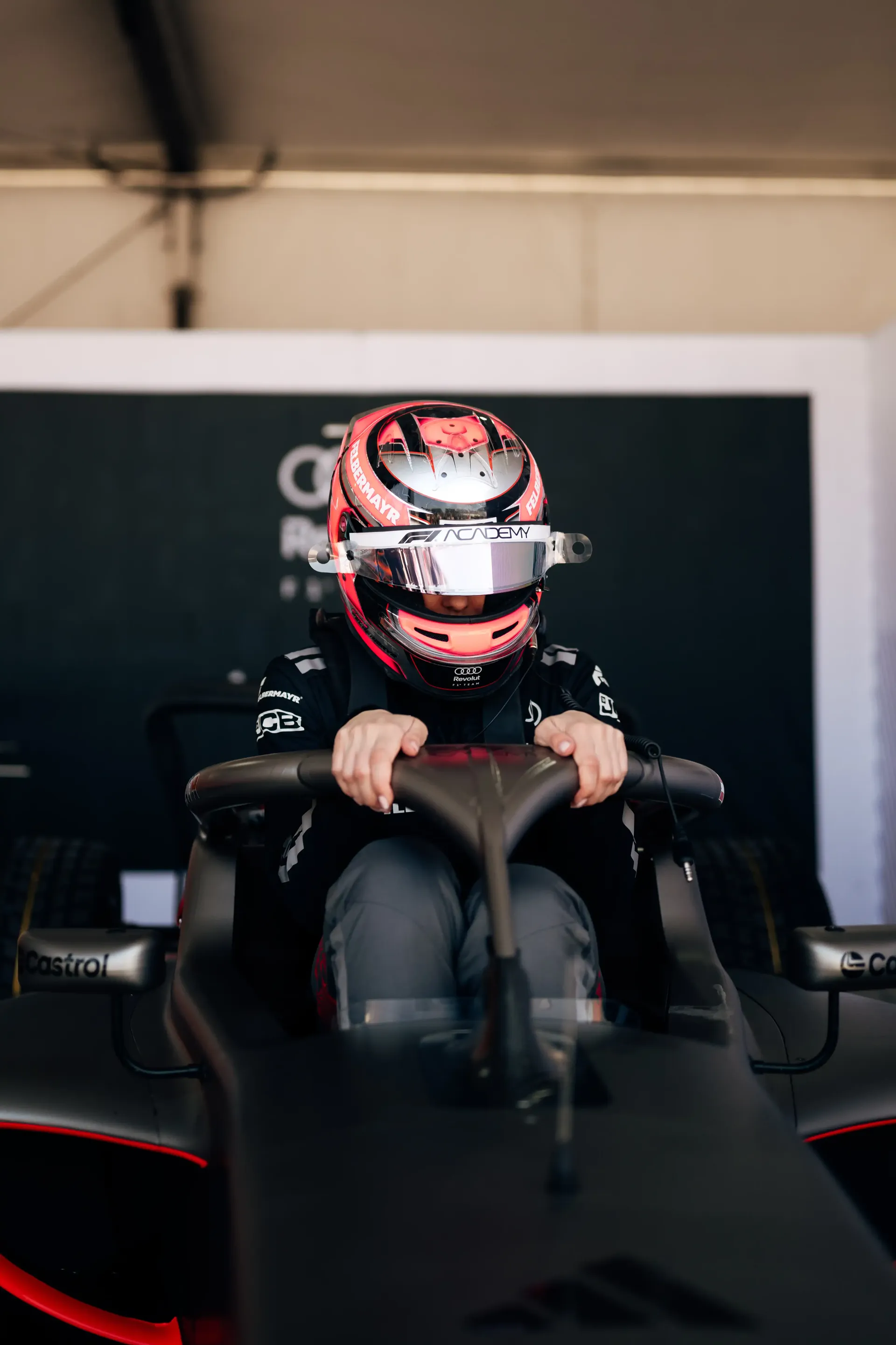 Emma Felbermayr, Audi Revolut F1® Team Academy driver, seated in the Formula 1 cockpit inside the garage preparing for track action.