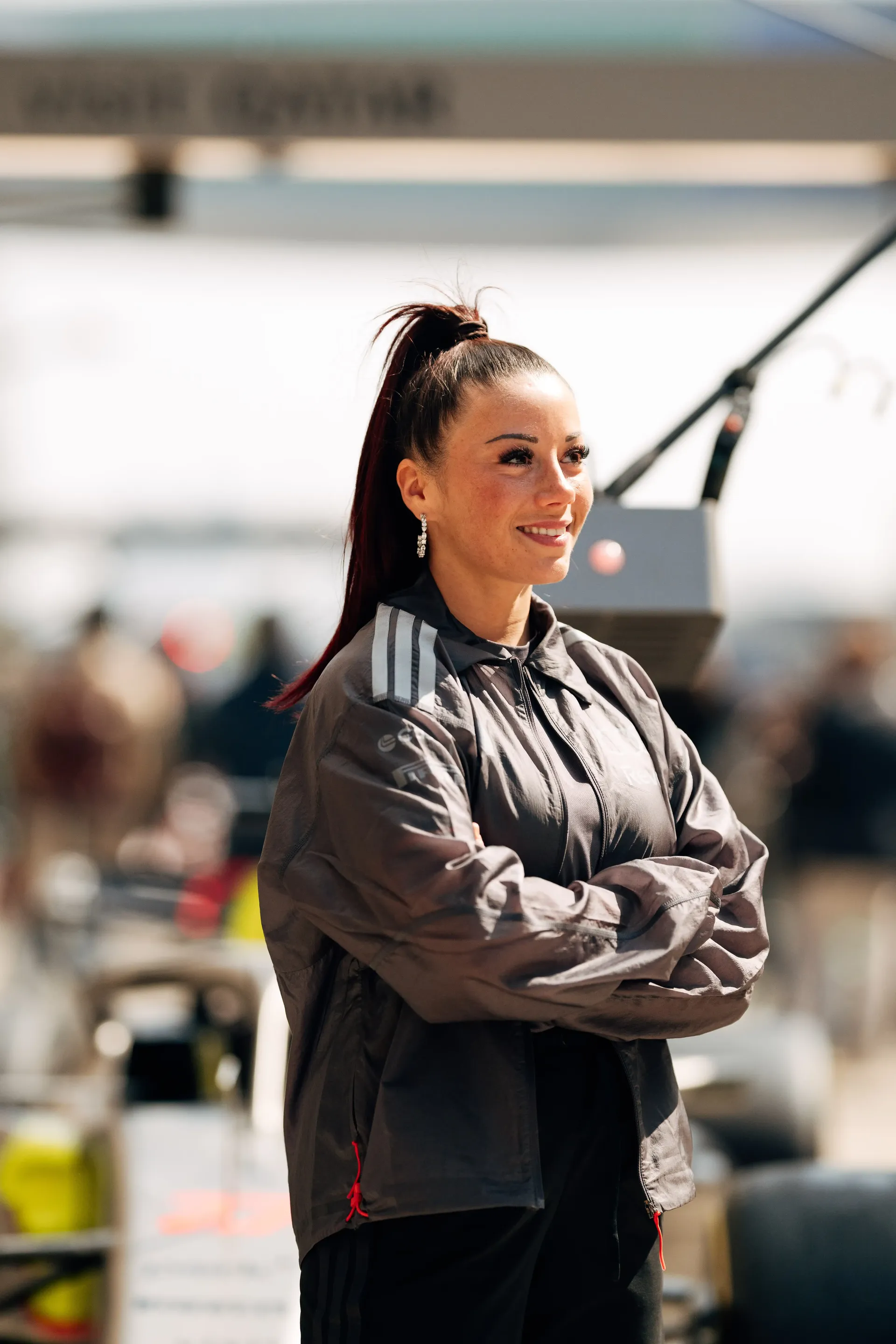 Carrie Schreiner close-up of Carrie with arms crossed, slight smile, blurred pit lane behind in China at Shanghai