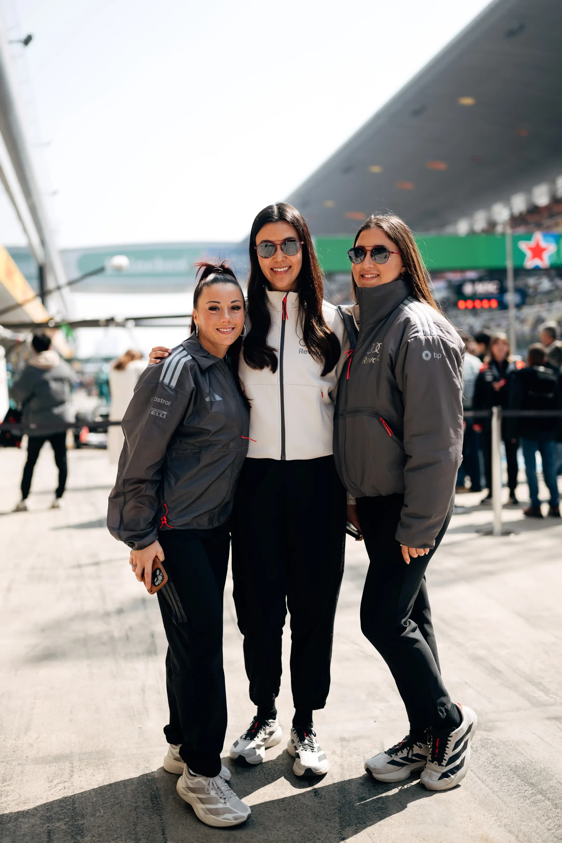 Carrie Schreiner standing with two team members in the Formula1® paddock during an Audi Revolut F1® Team Academy race event in China at Shanghai