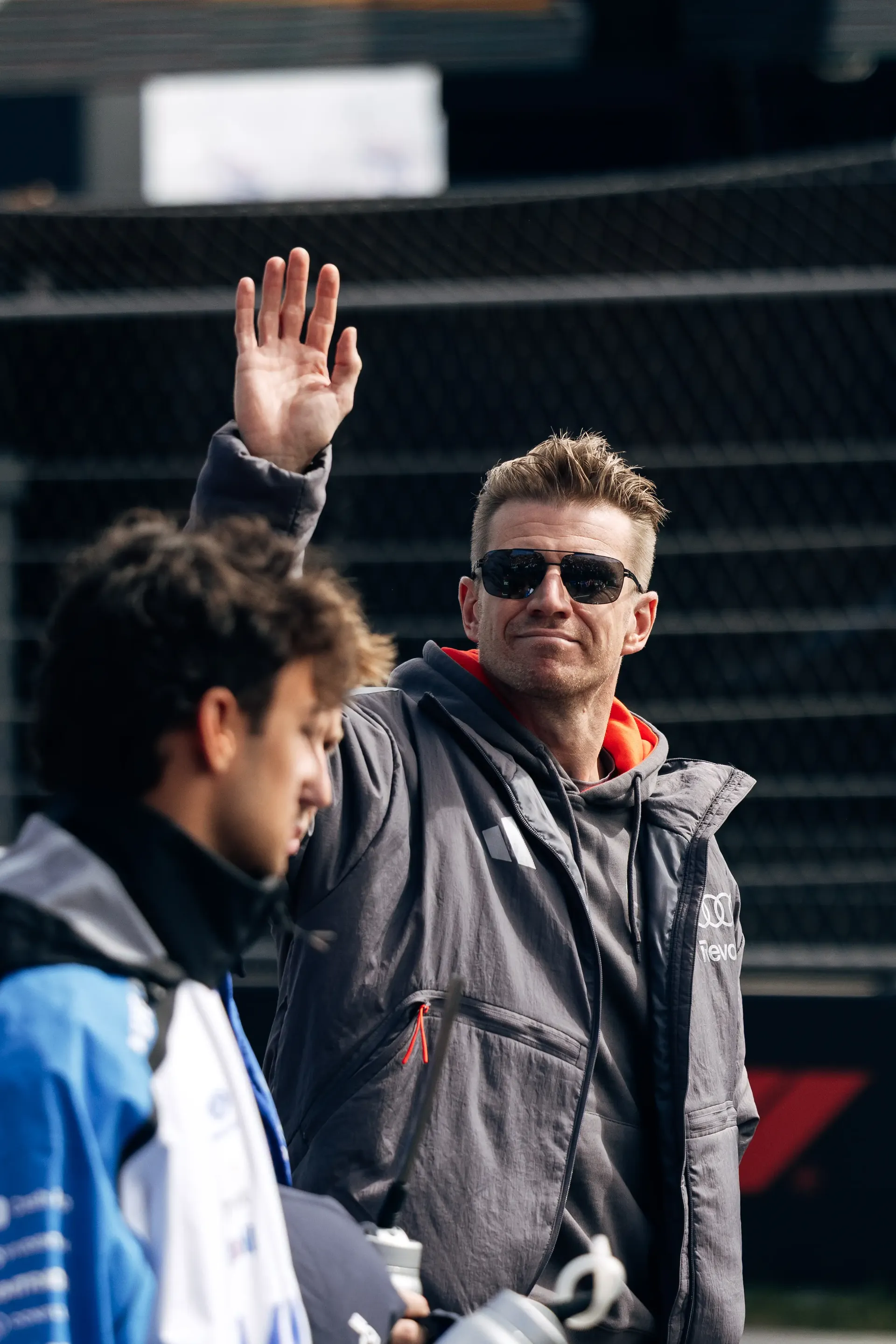 Nico Hulkenberg waves to fans while Gabriel Bortoleto stands nearby during an Audi Revolut F1® Team fan parade at the Dutch Grand Prix.