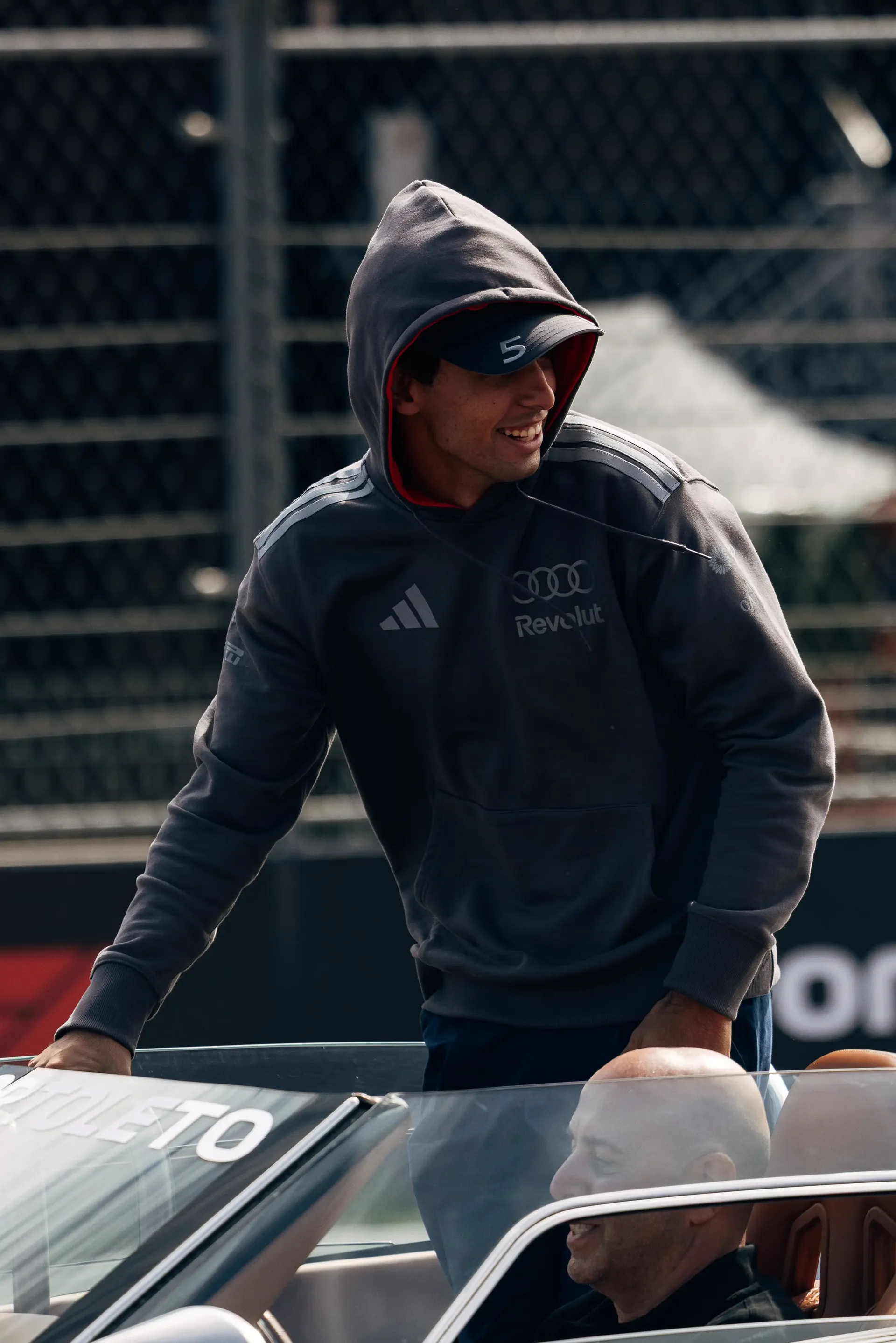 Gabriel Bortoleto standing in an Audi Revolut F1® Team parade car wearing a team hoodie during the Dutch Grand Prix.