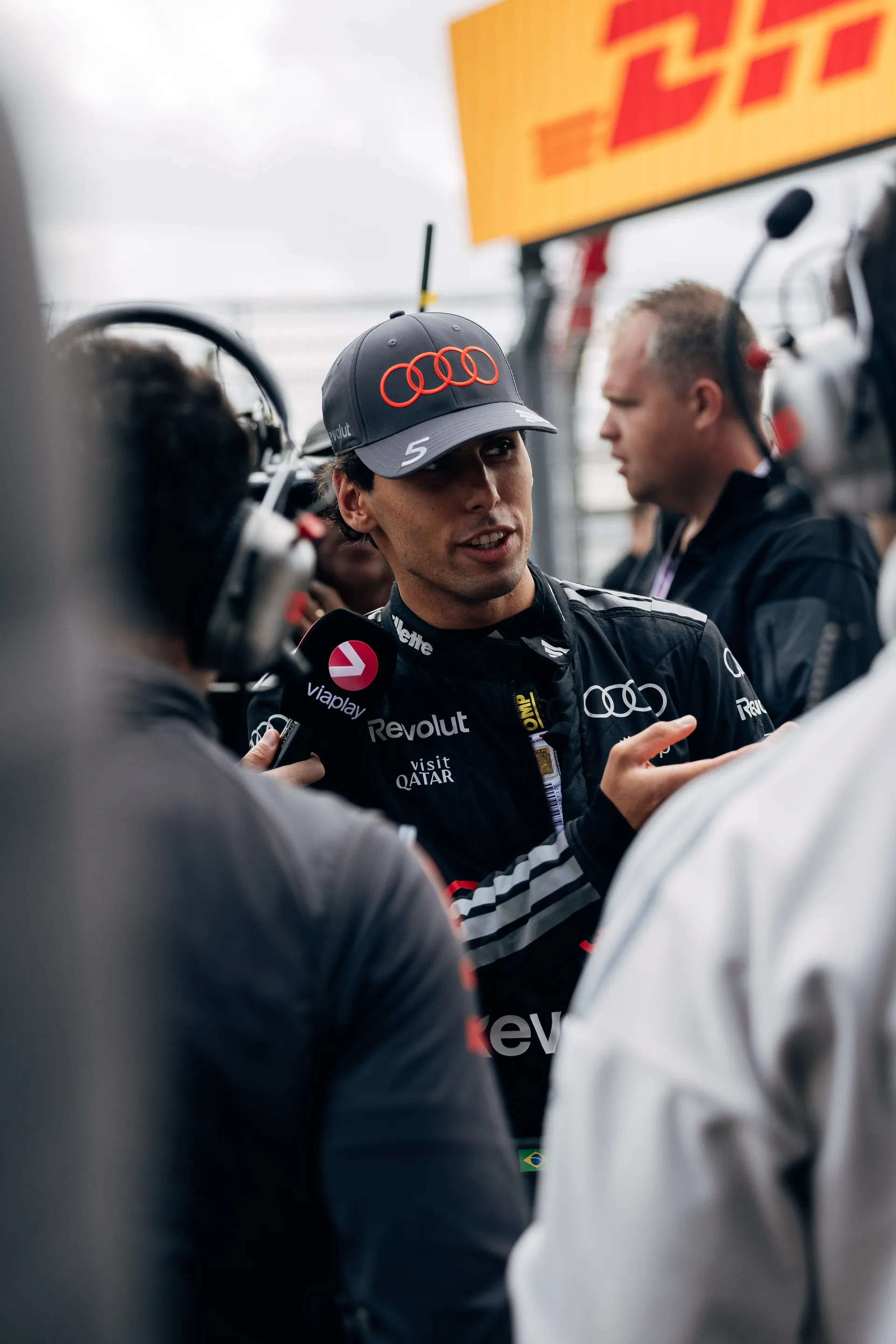 Audi Revolut F1® Team driver Gabriel Bortoleto standing in the paddock with team members.
