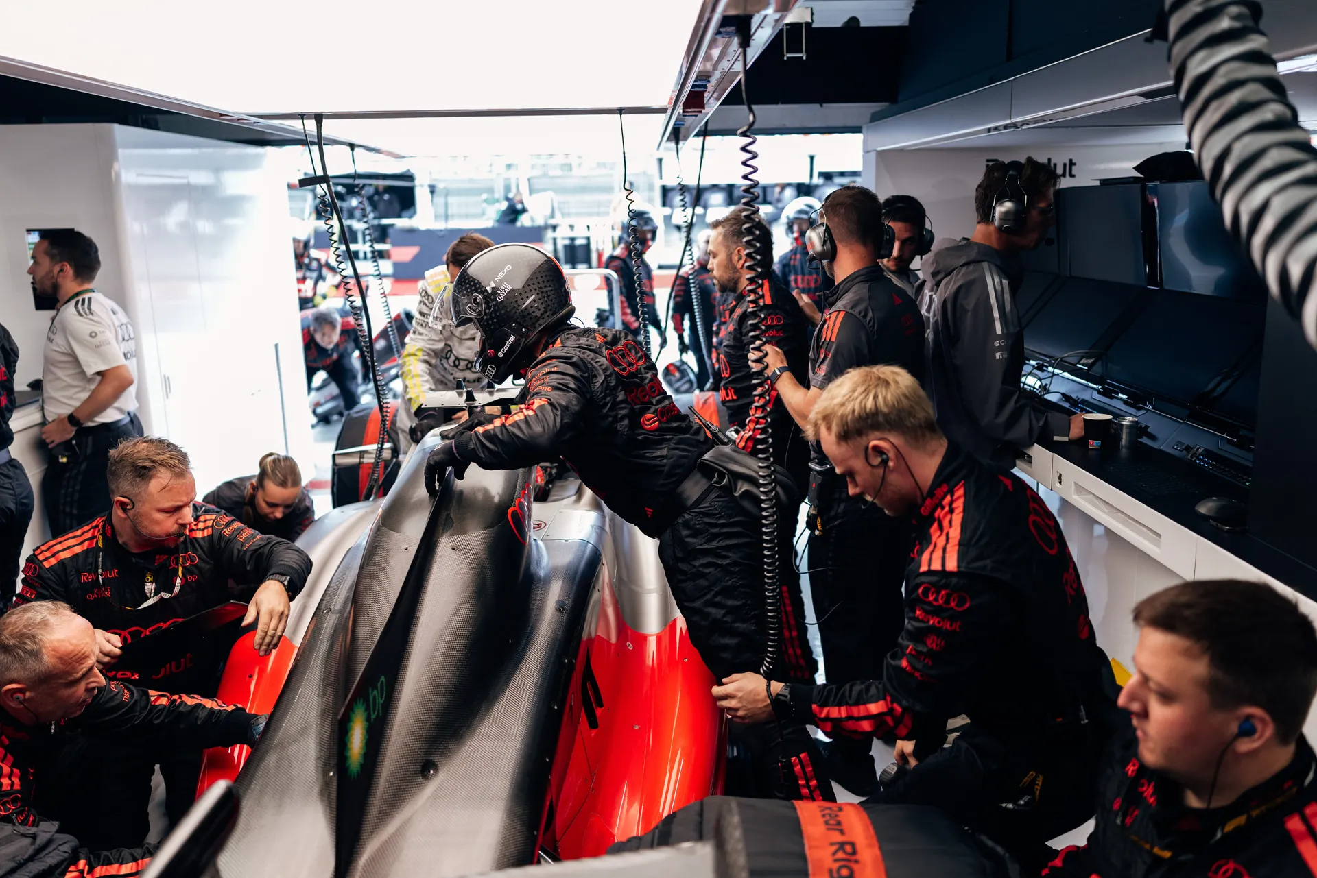 Audi Revolut F1® Team mechanics working around the Audi R26 team car in the garage.