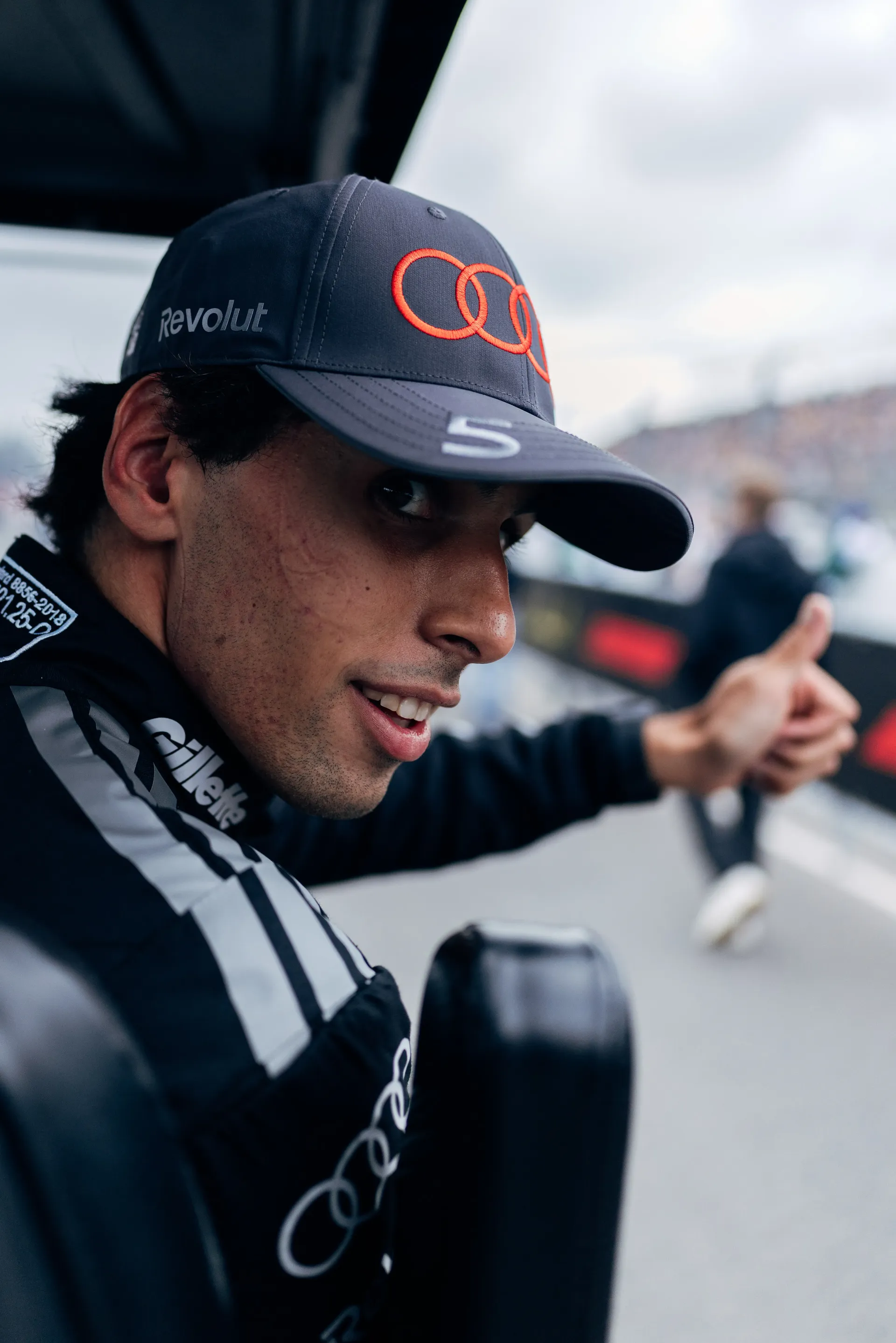 Close-up of Audi Revolut F1® Team driver Gabriel Bortoleto in the paddock, smiling and giving a thumbs up.