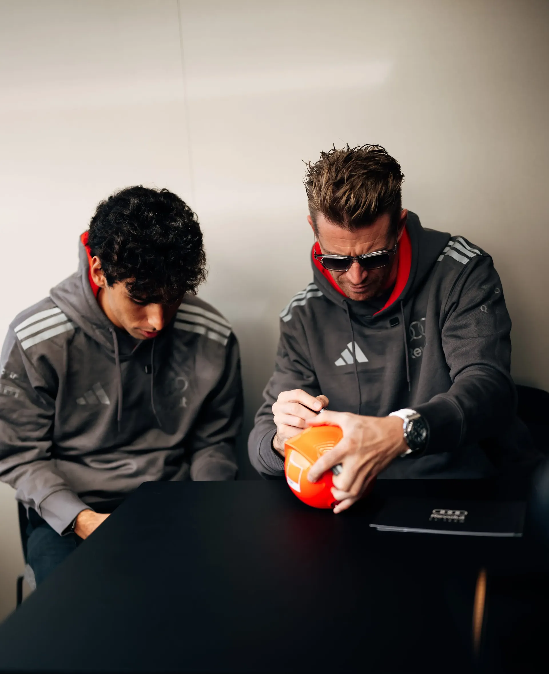 Nico Hulkenberg of the Audi Revolut F1® Team signing a cap next to Gabriel Bortoleto