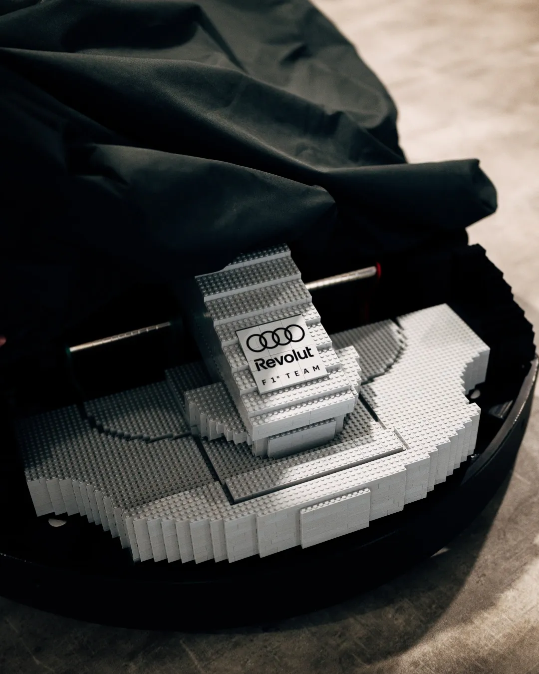Close-up of a sneaker resting on the bodywork of a full-size LEGO Audi Formula-style race car on display at the British Grand Prix.
