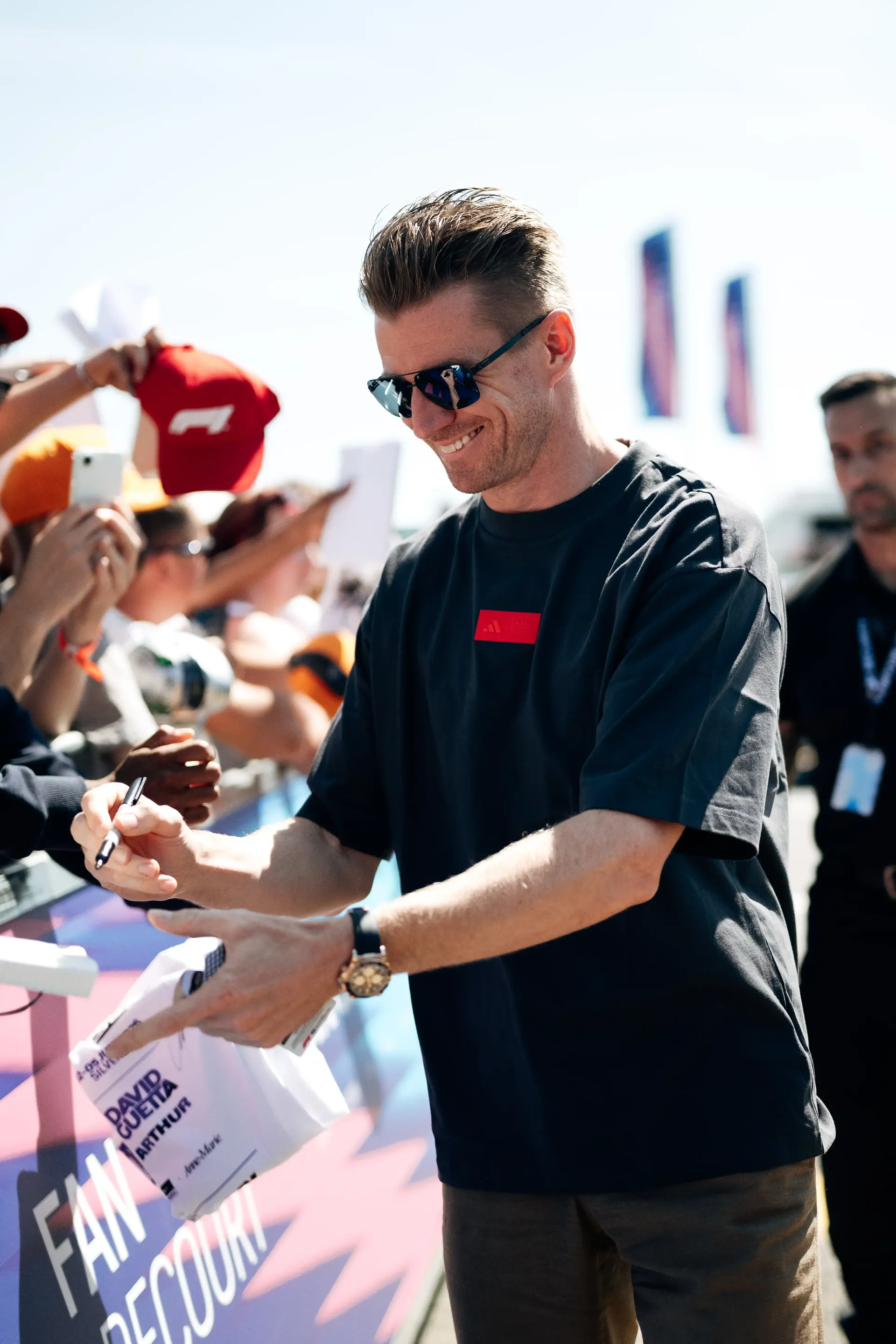 Nico Hulkenberg, driver at the Audi Revolut F1® Team, signs autographs during his arrival at the British Grand Prix wearing the adidas Elevated Fanwear Collection.