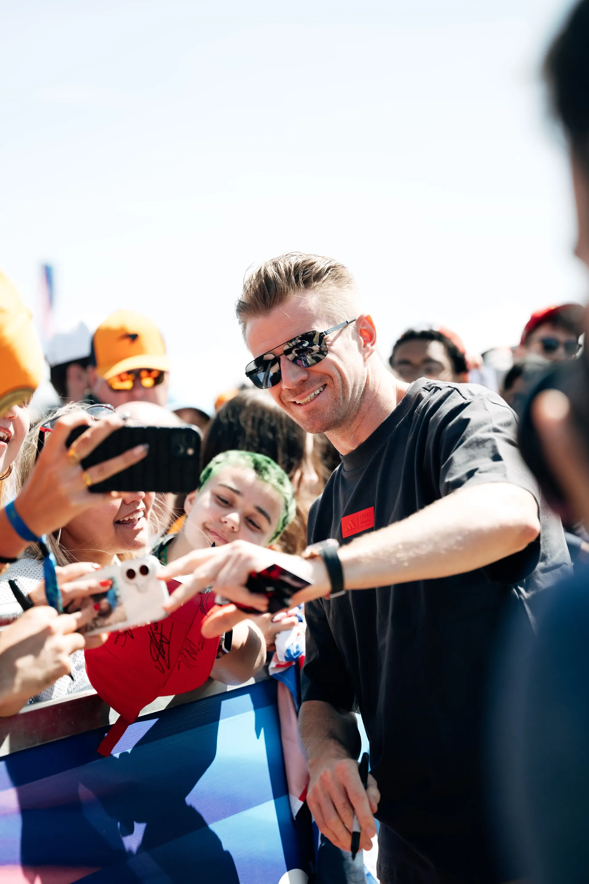 Nico Hulkenberg, driver at the Audi Revolut F1® Team, signs memorabilia for fans during his arrival at the British Grand Prix wearing the adidas Elevated Fanwear Collection.