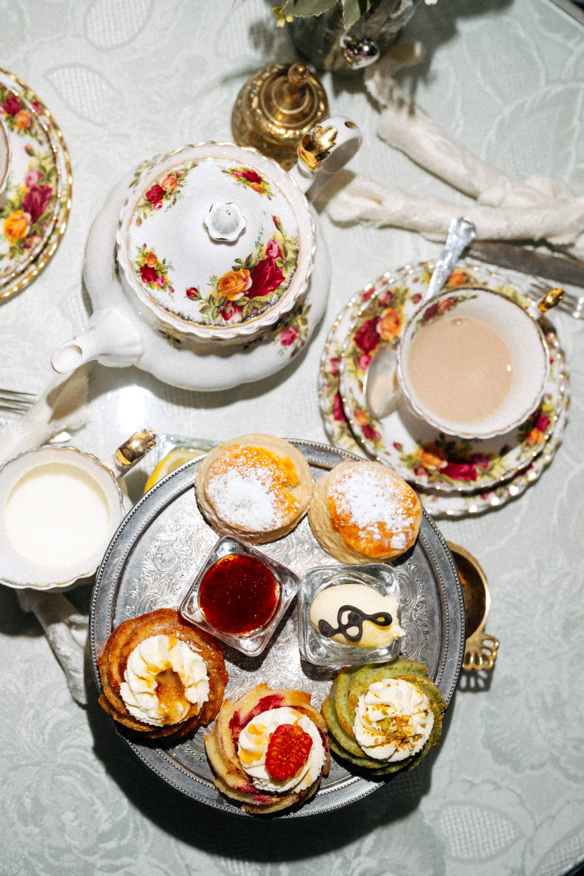 Overhead view of an elegant afternoon tea with teacups, cakes, and pastries.