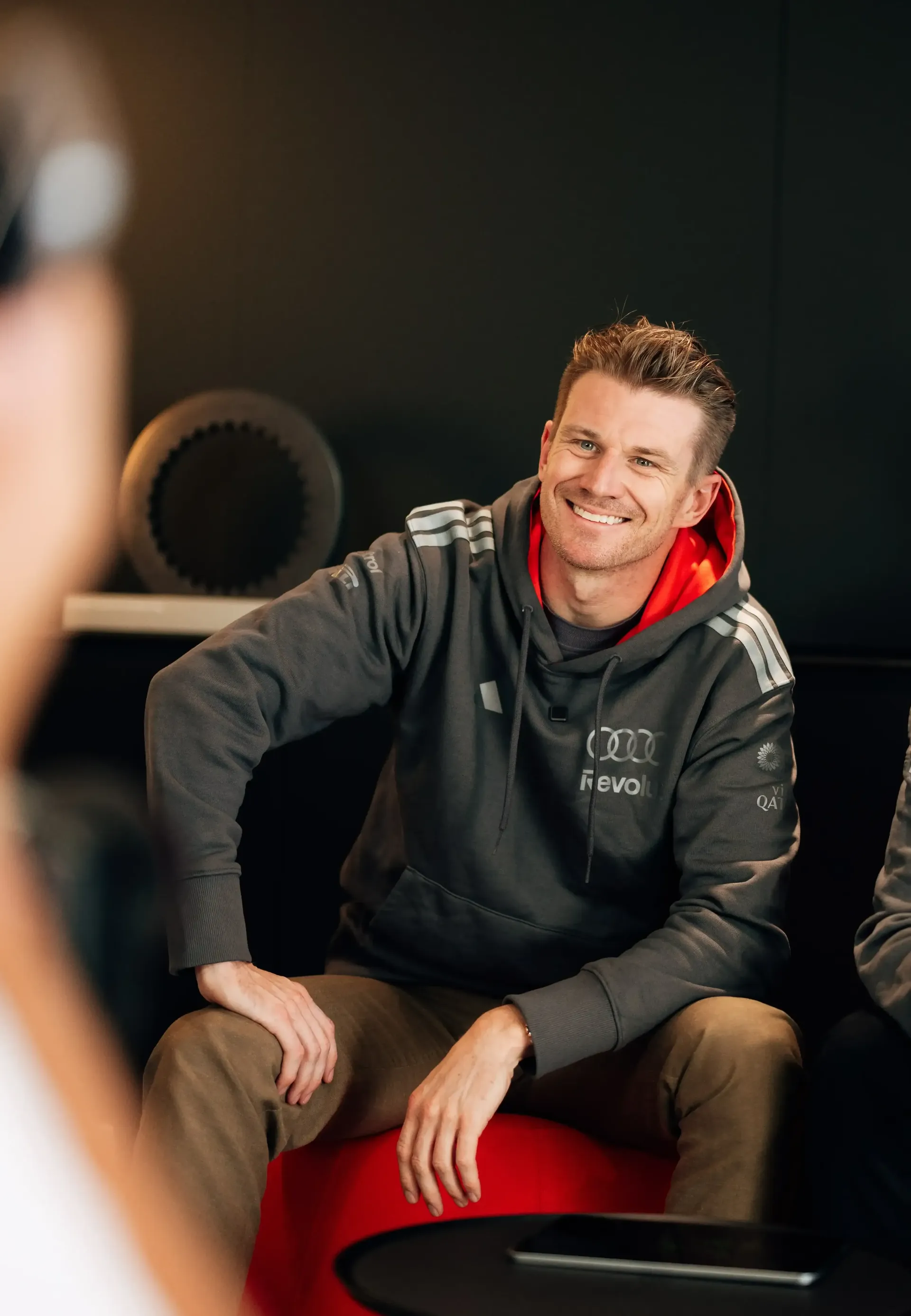 Nico Hulkenberg driver at the Audi Revolut F1® Team inside the hospitality Audi Hub sitting on the couch in realxed and proud pose smiling at the camera