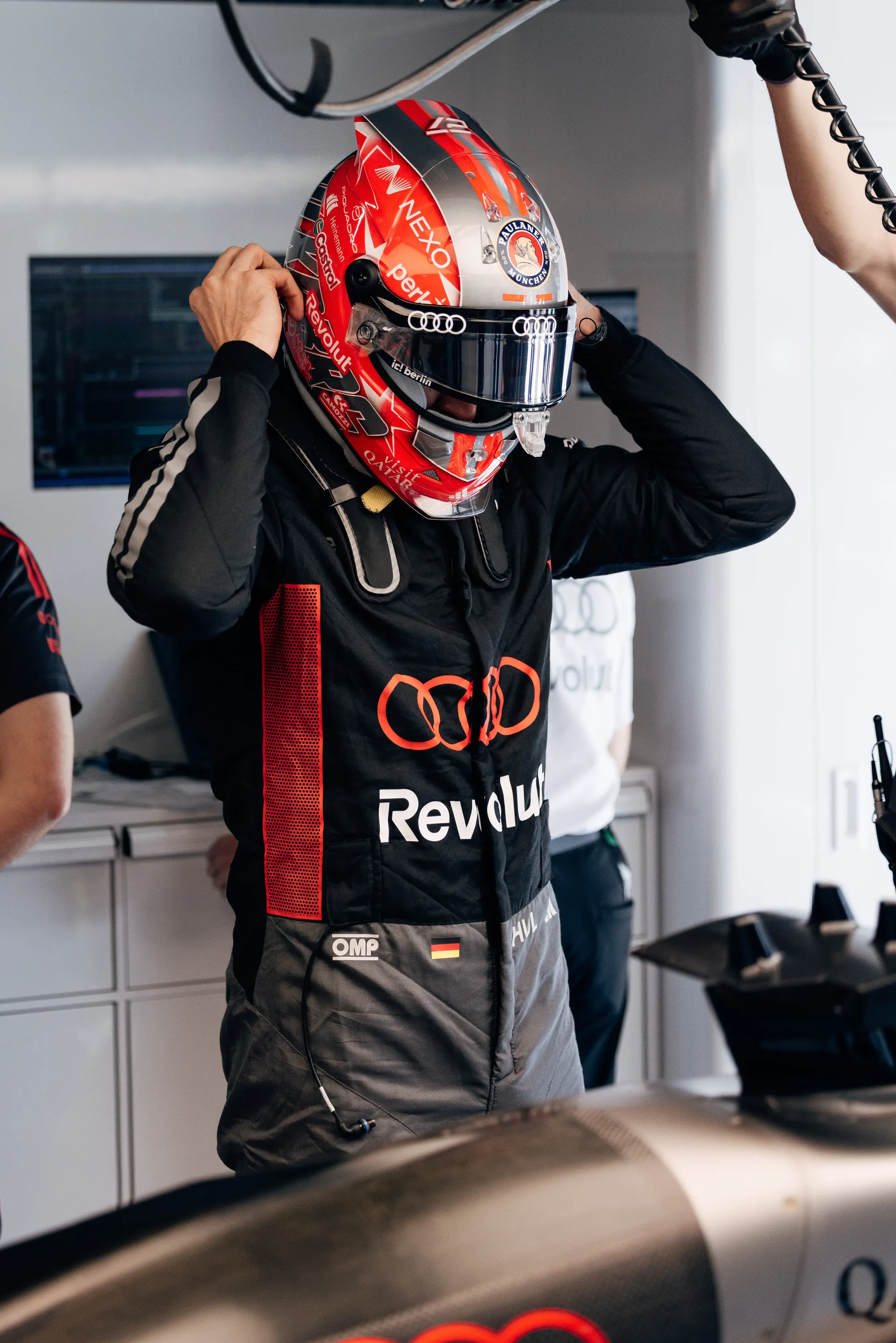 Driver adjusts helmet beside the Audi R26 in the garage before heading out.