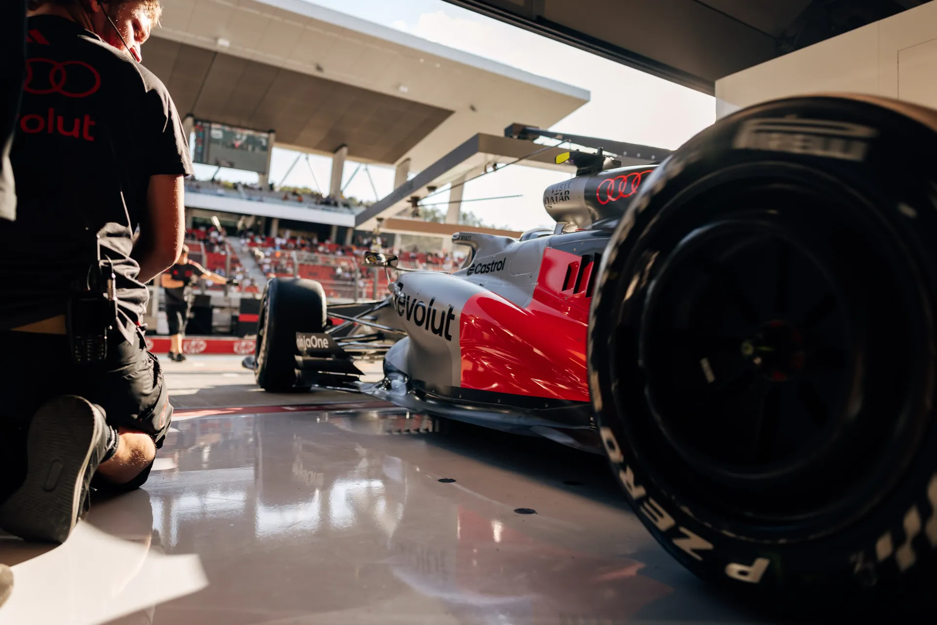 Low-angle view of the Audi Revolut F1® Team car Audi R26 in the garage with the front tyre in the foreground before FP2.
