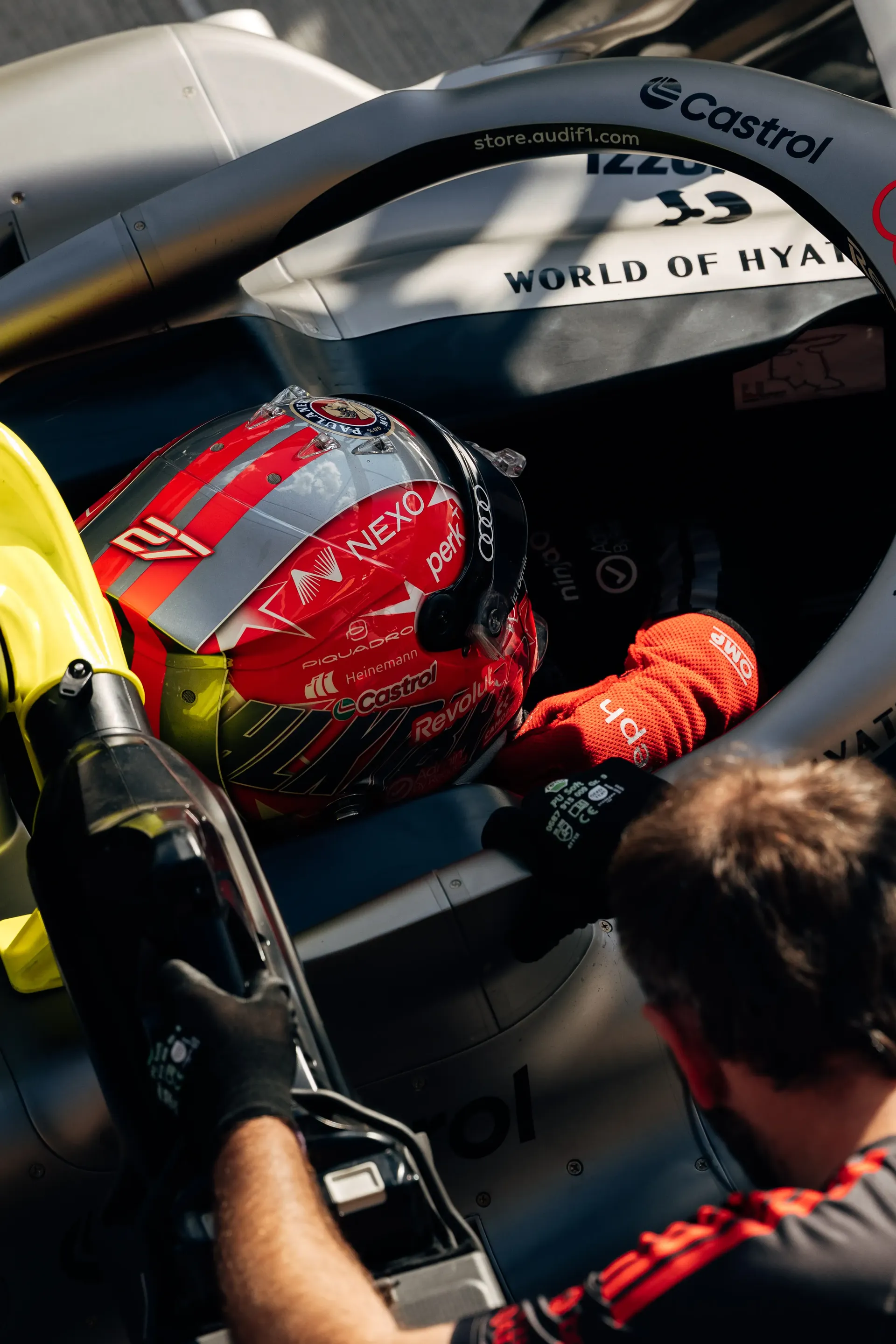 Close-up of Audi Revolut F1® Team driver Nico Hulkenberg in the cockpit of the Audi Revolut F1® Team car Audi R26 as an Audi Revolut F1® Team mechanic assists before leaving the garage.