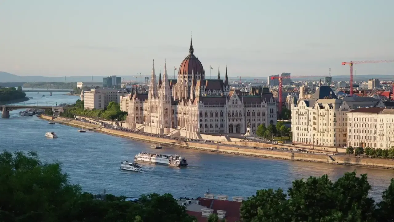 A drone view of the Hungarian Parliament Building in Budapest, overlooking the Danube and the city's historic skyline.