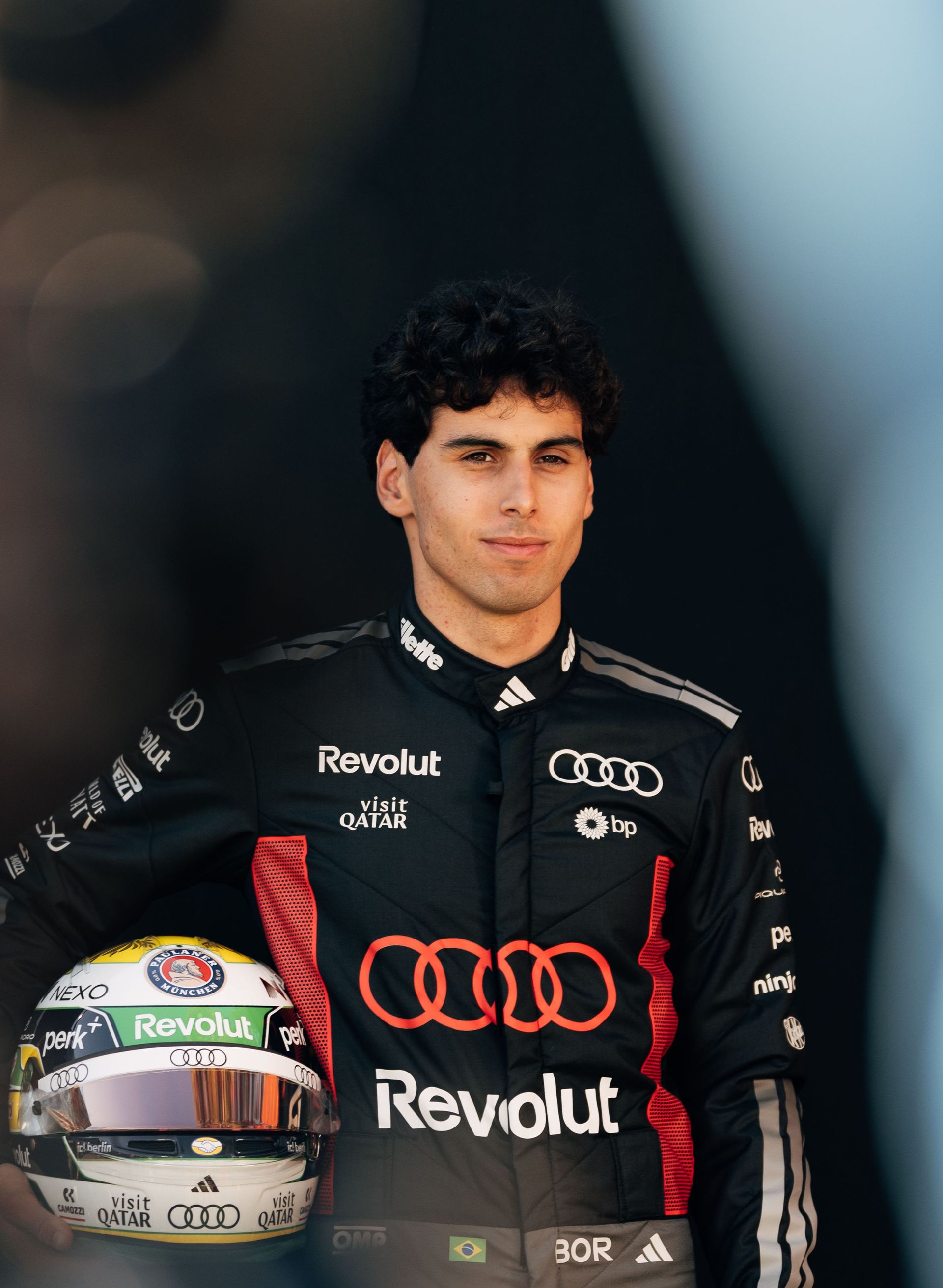 Audi Revolut F1® Team driver Gabriel Bortoleto holding his helmet at the side of the racetrack