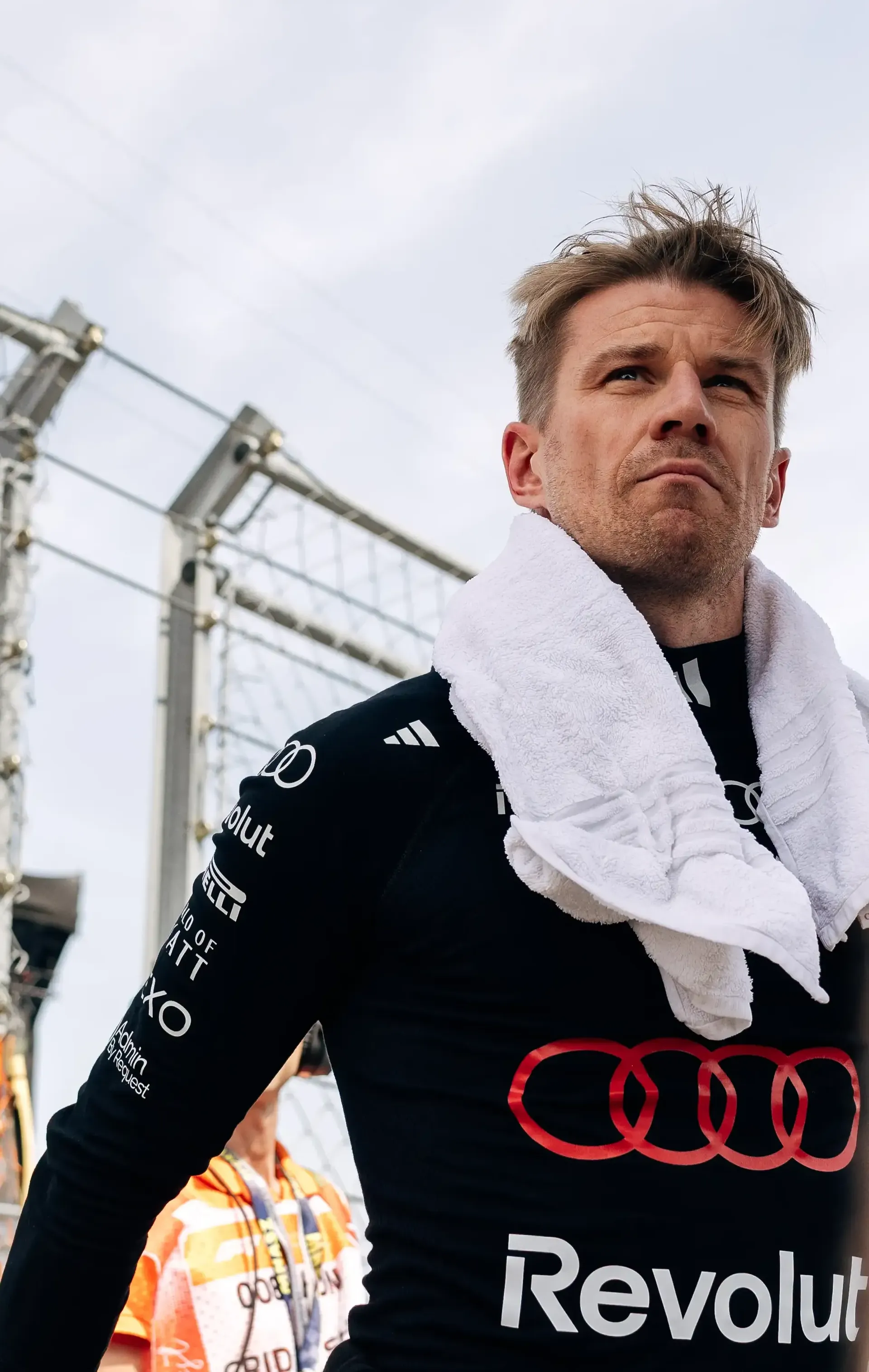 Audi Revolut F1® Team driver Nico Hulkenberg walks through the Hungaroring paddock wearing his race suit with a towel over his shoulders.